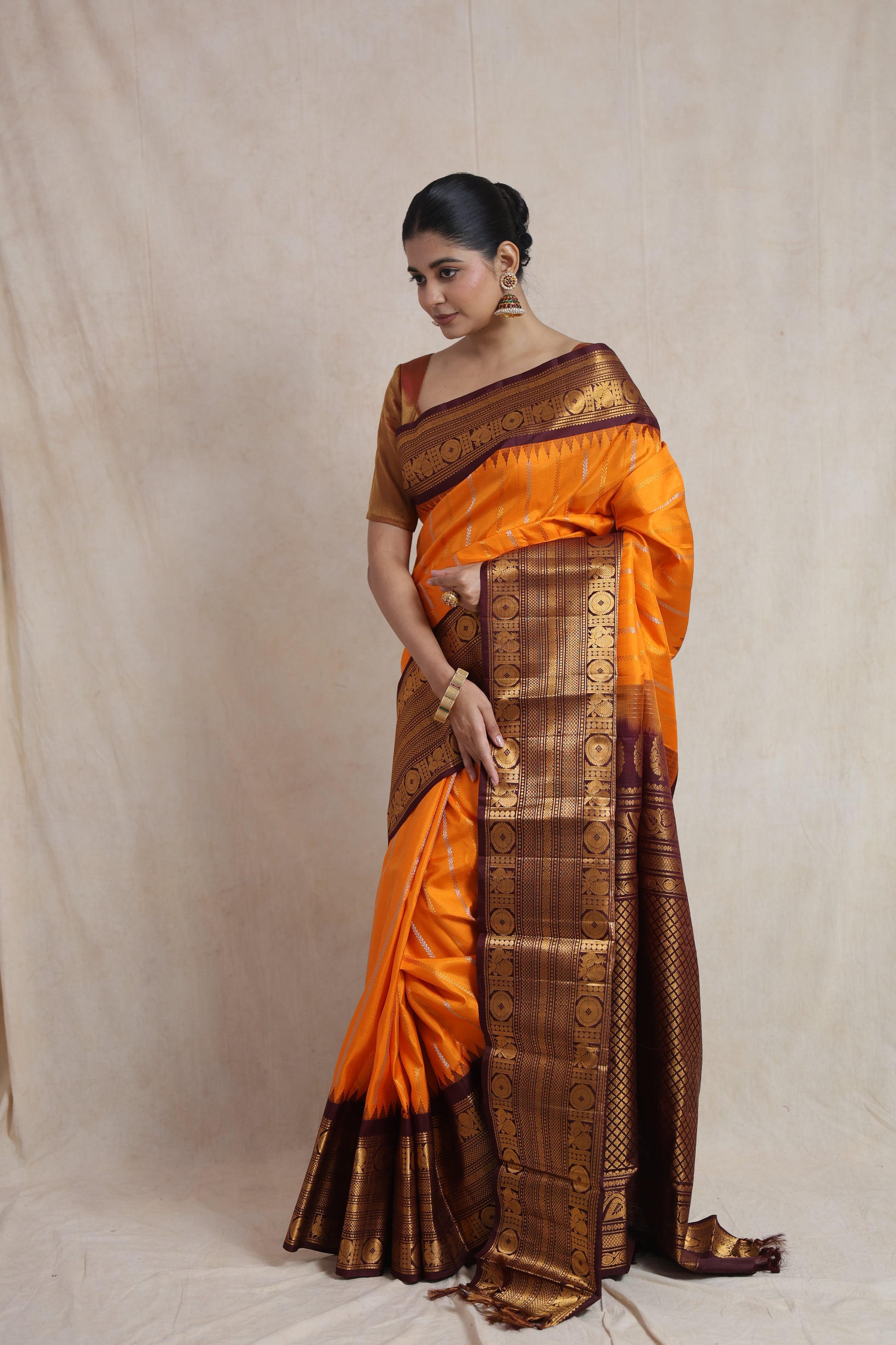 Side profile of a model wearing a burnt orange Gadwal silk saree featuring a rich contrast border and luxurious silk texture.