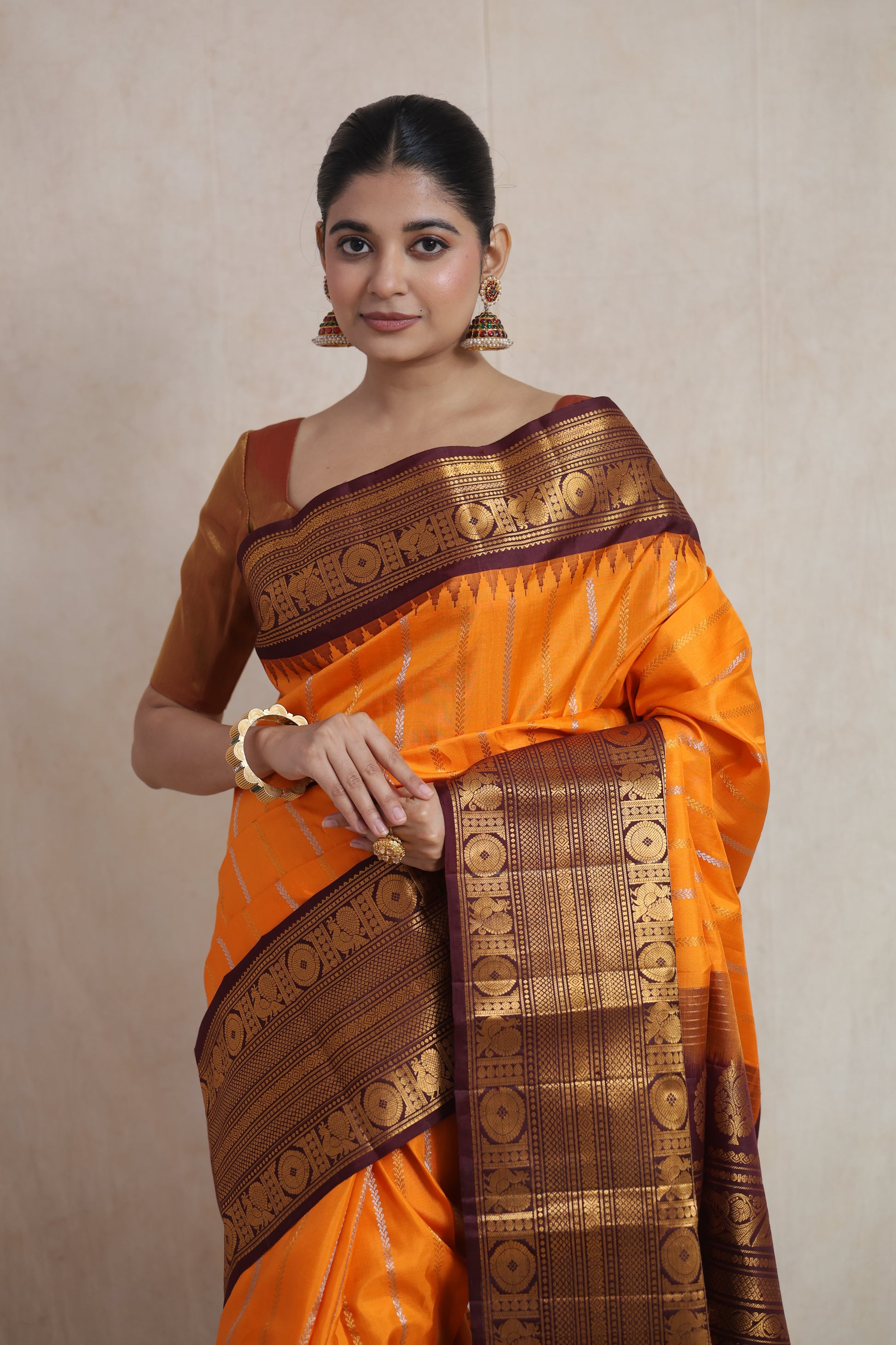 Close-up of the burnt orange Gadwal silk saree showcasing the fine weave, striped body, and detailed border.