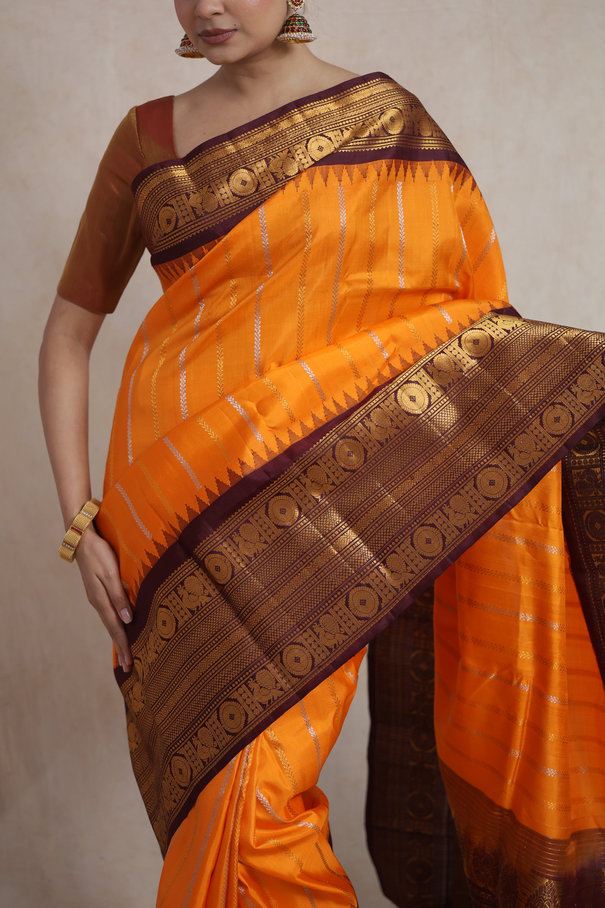 Close-up of the burnt orange Gadwal silk saree showcasing the fine weave, striped body, and detailed border.