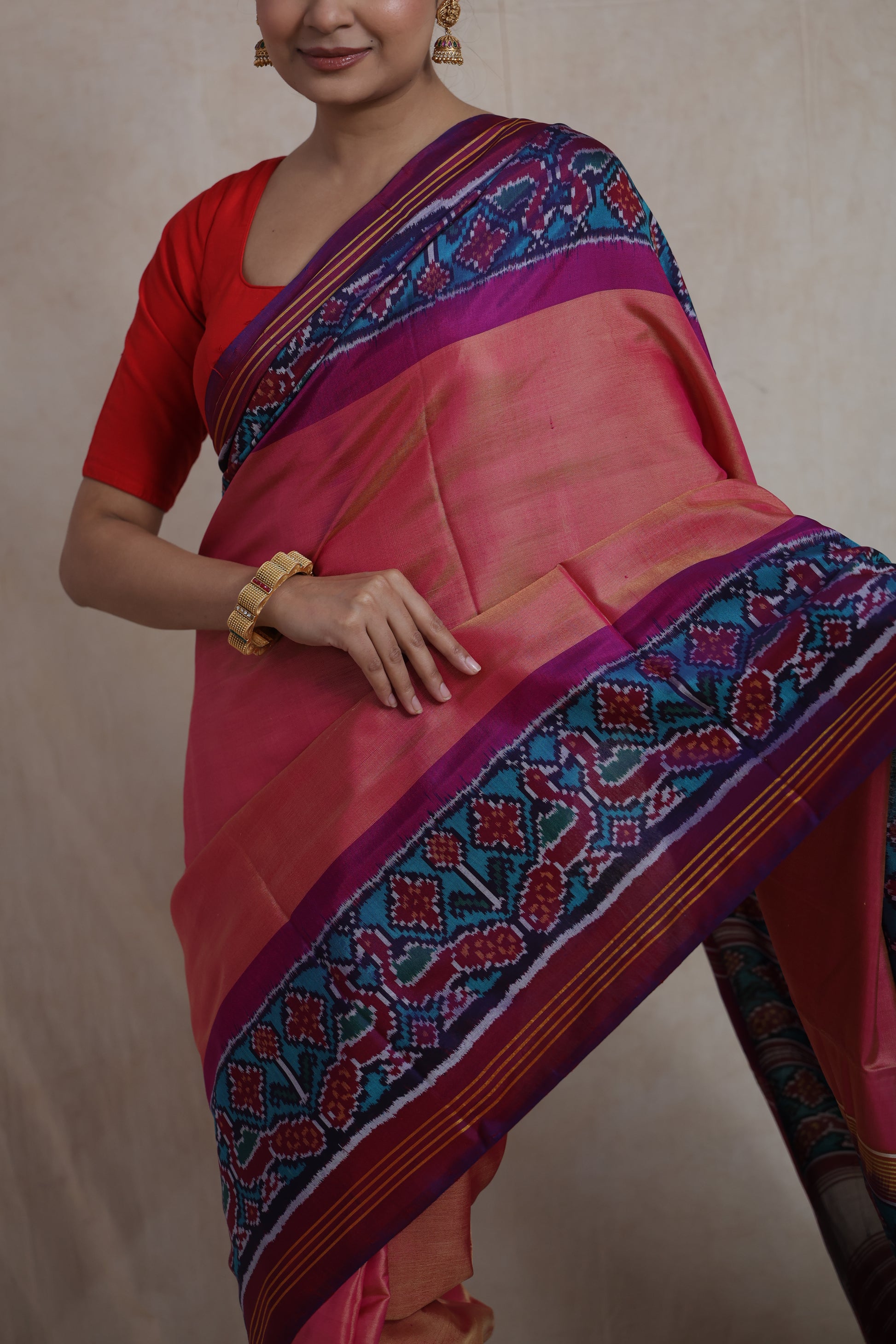 Detailed drape of peach pink Patola silk saree with traditional Ikat woven border