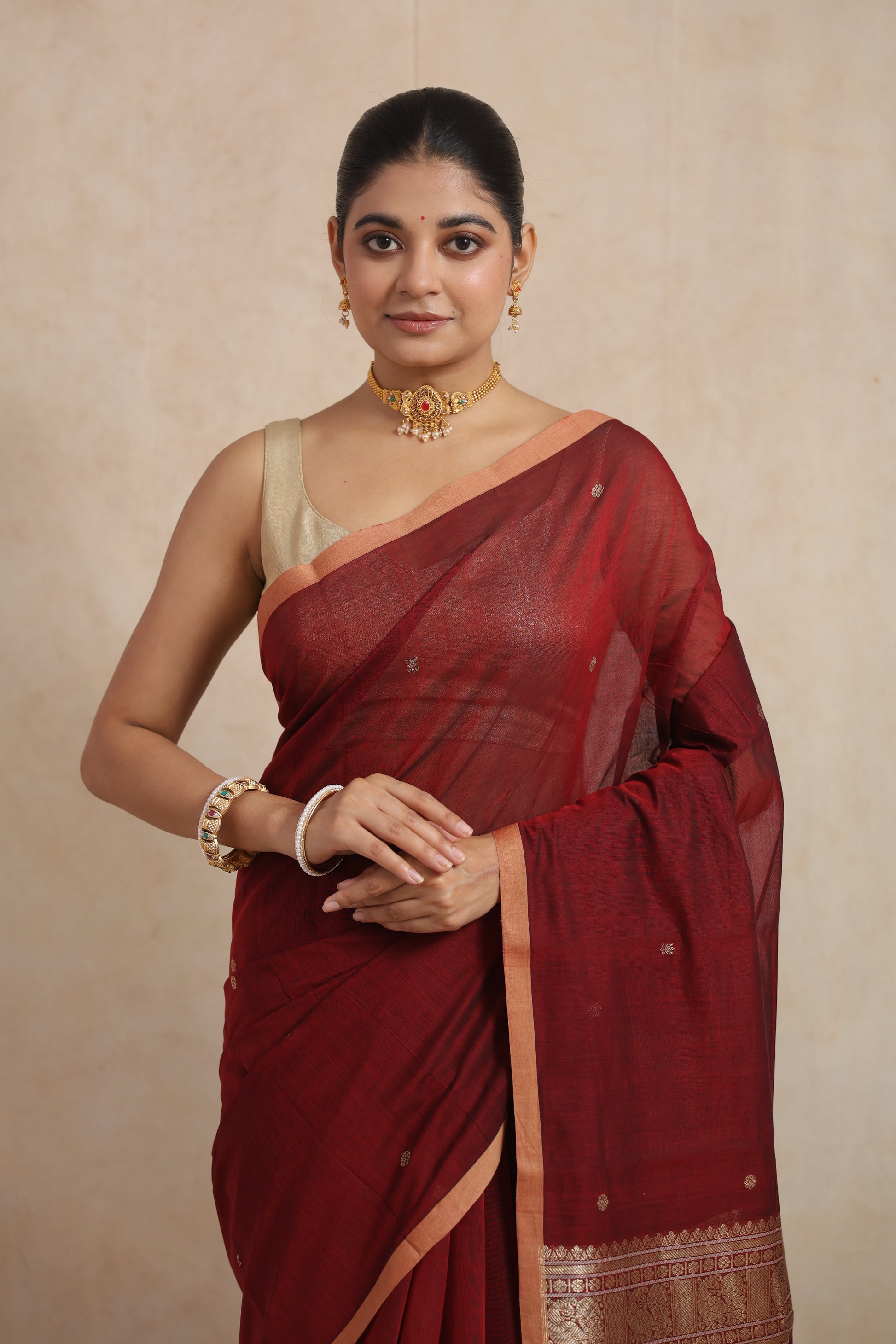 Close-up of the maroon Kanchipuram cotton saree highlighting the woven motifs, fine cotton texture, and elegant border.