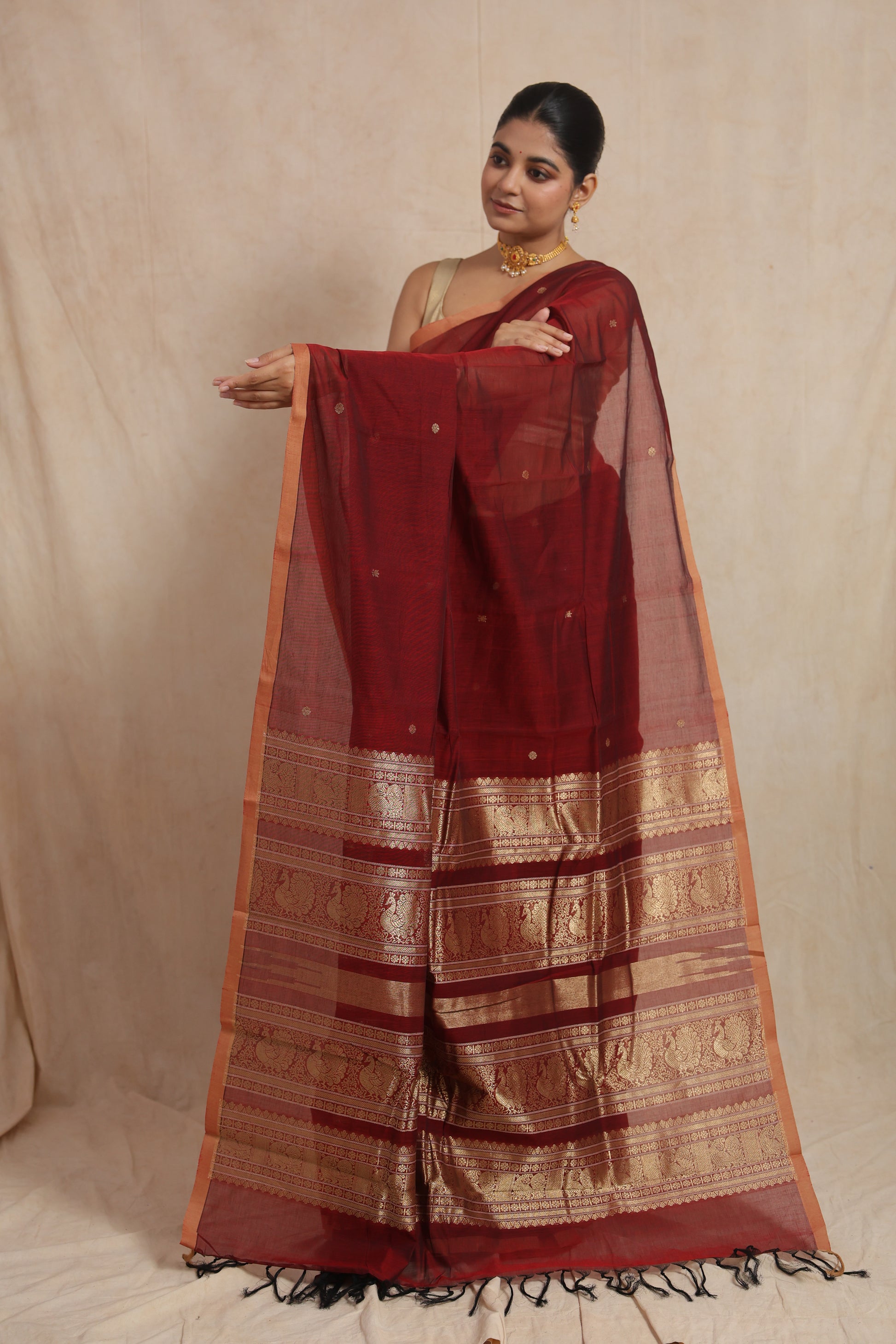 Detailed view of the traditional woven pallu and border of the maroon Kanchipuram cotton saree.