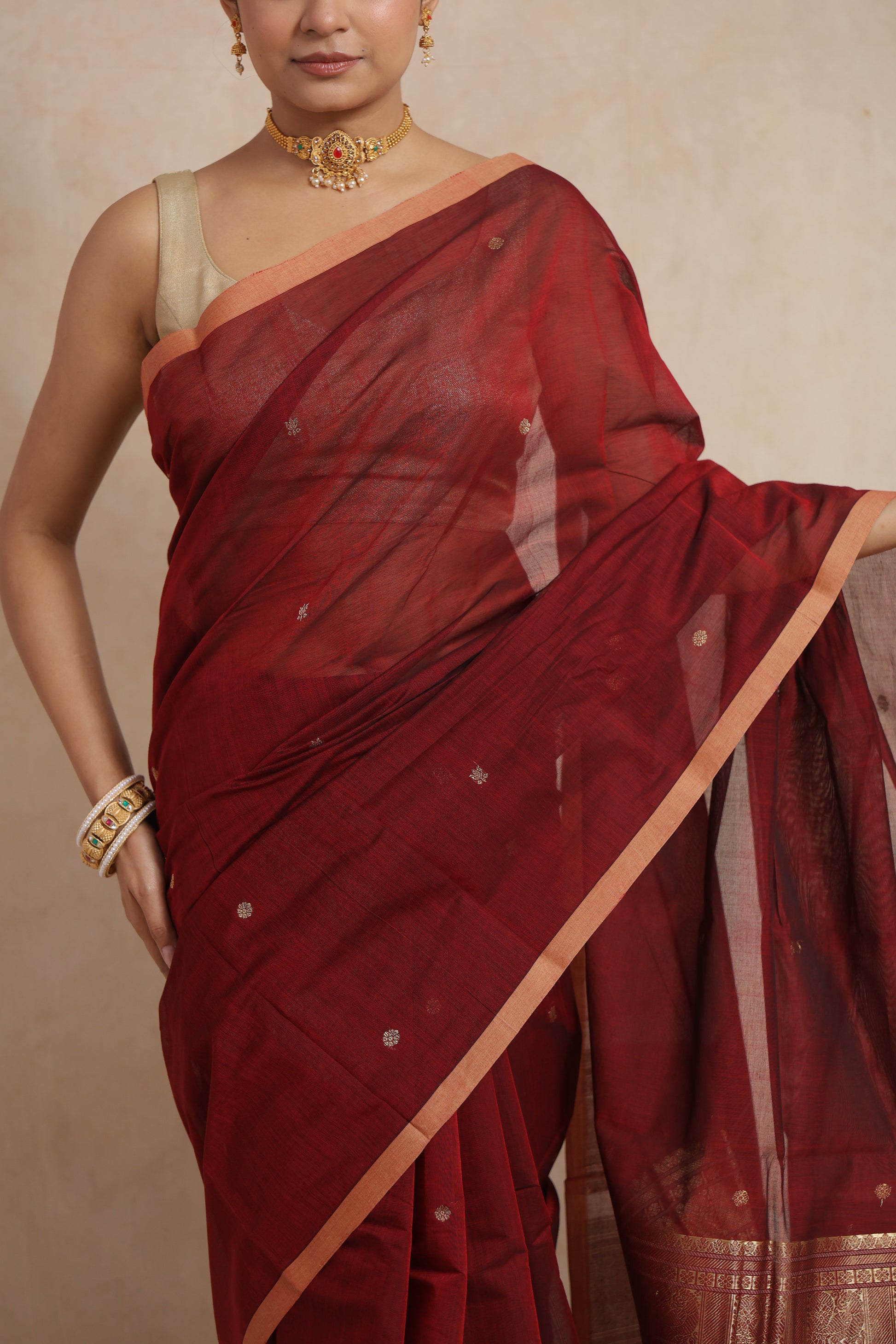 Model wearing a maroon Kanchipuram cotton saree with an elegant woven border and handcrafted pallu.