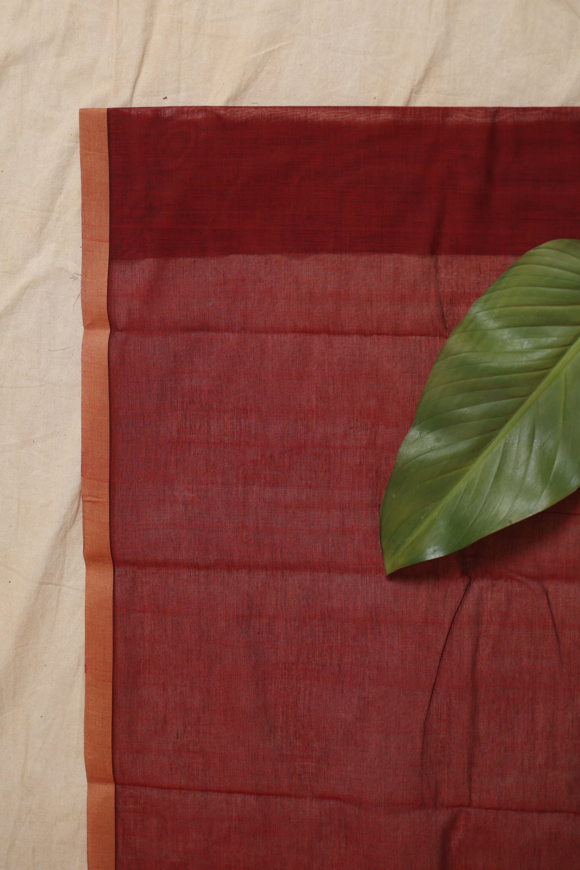 Flat-lay view of the maroon Kanchipuram cotton saree displaying its woven border, pallu, and premium cotton weave.