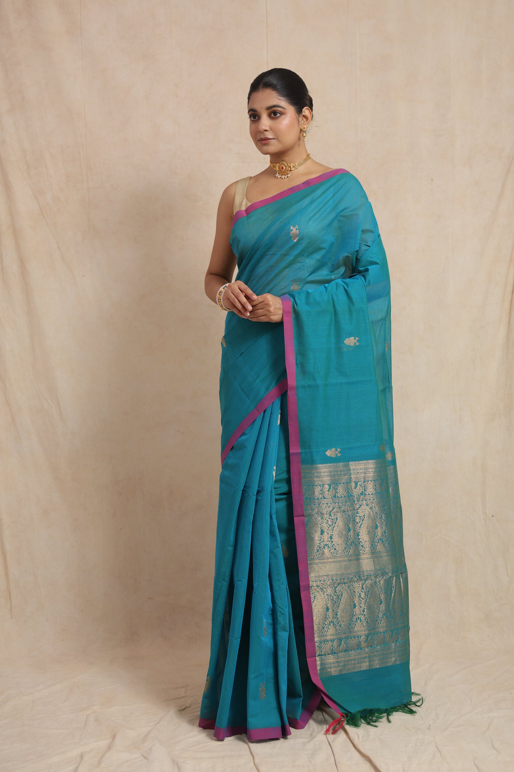 Elegant drape of turquoise blue cotton saree featuring contrast magenta border
