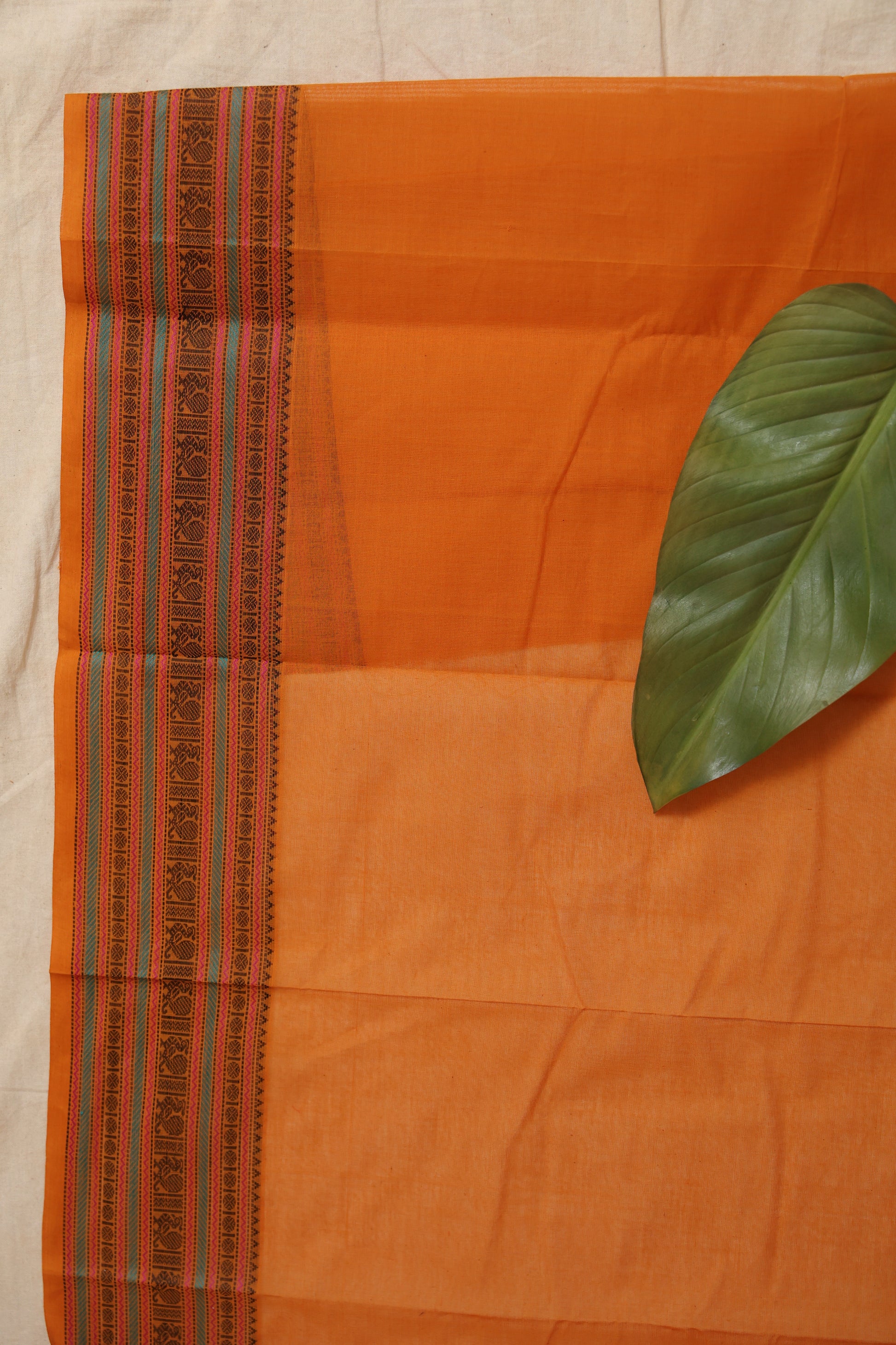 Border detail of sunset orange Kanchipuram handloom cotton saree with intricate traditional weaving