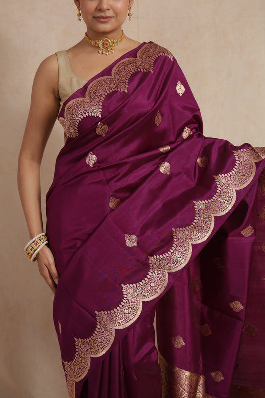 Close-up of royal magenta Banarasi art silk saree showcasing intricate scalloped woven border and buttas