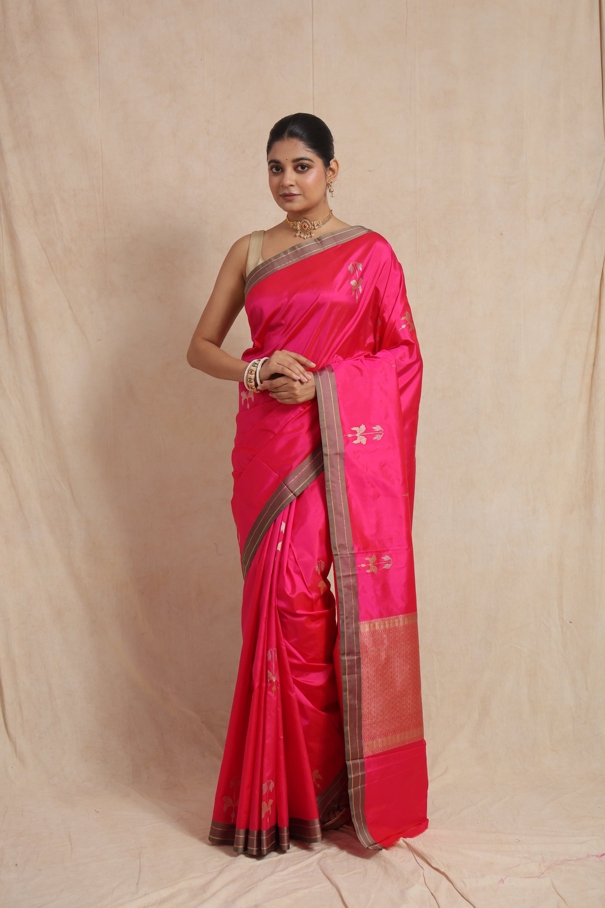 Front view of a hot pink Banarasi silk saree featuring woven floral buttas, contrast border, and rich pallu.