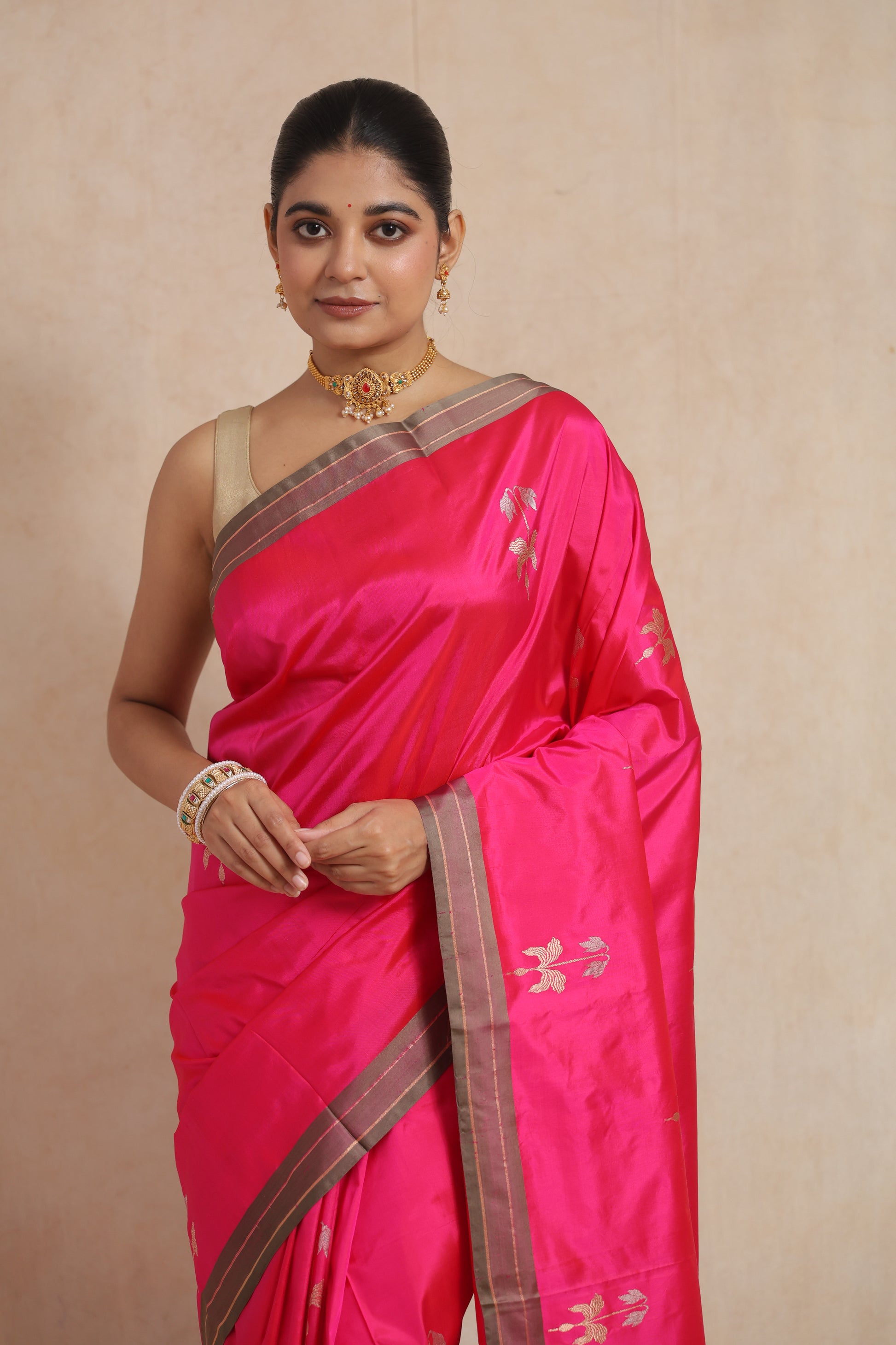 Close-up of the hot pink Banarasi silk saree showcasing delicate woven floral buttas and luxurious silk texture.