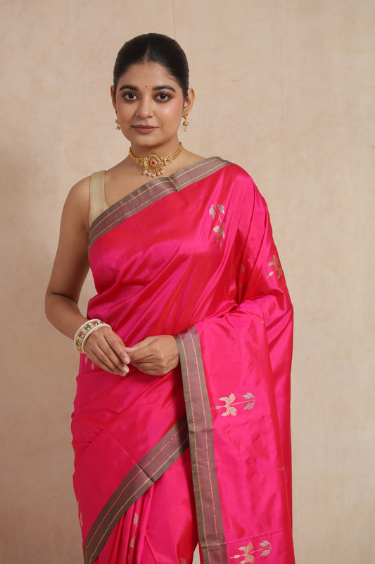 Close-up of the hot pink Banarasi silk saree showcasing delicate woven floral buttas and luxurious silk texture.