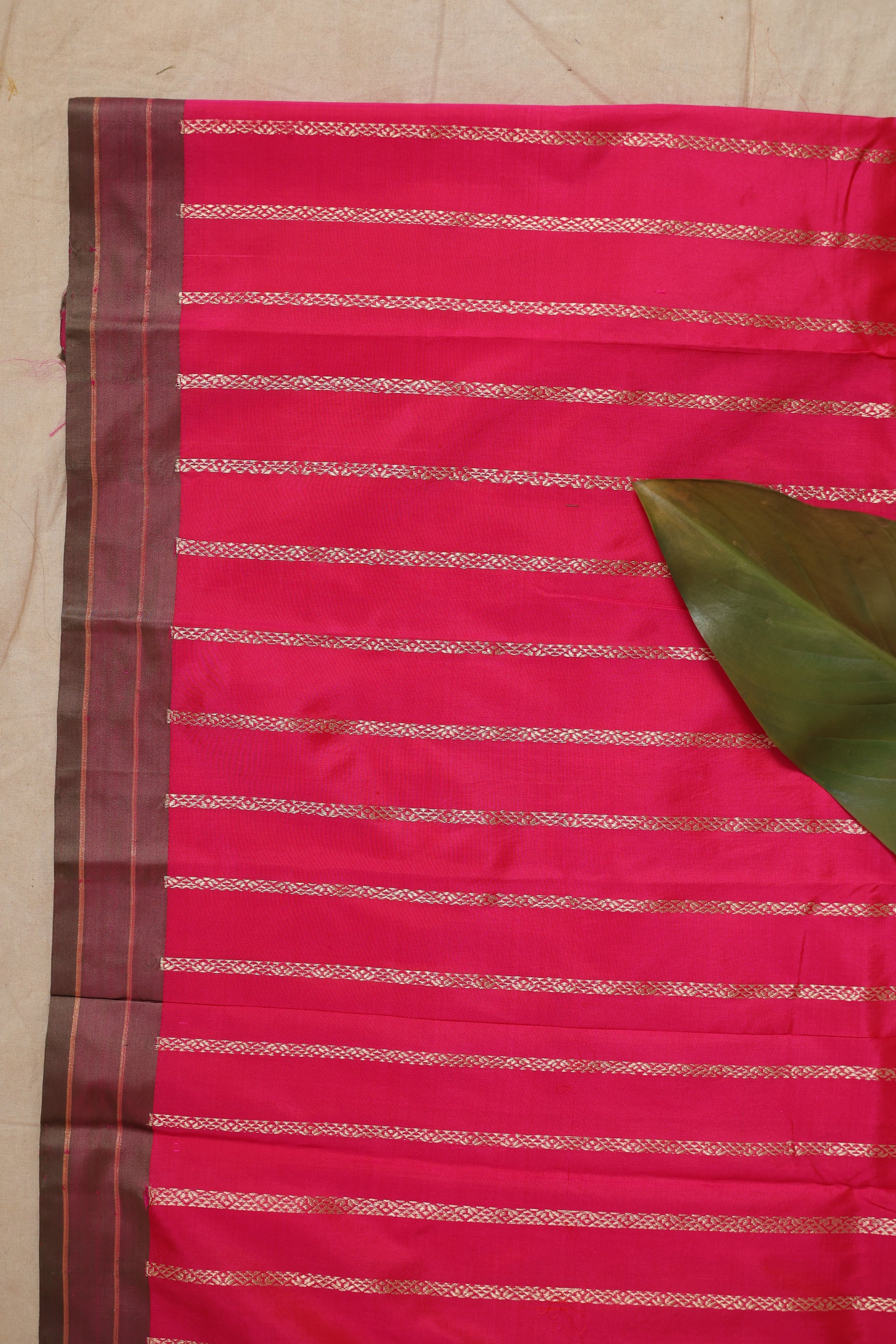 Fabric close-up of the hot pink Banarasi silk saree showing intricate woven stripes, floral motifs, and premium silk finish.