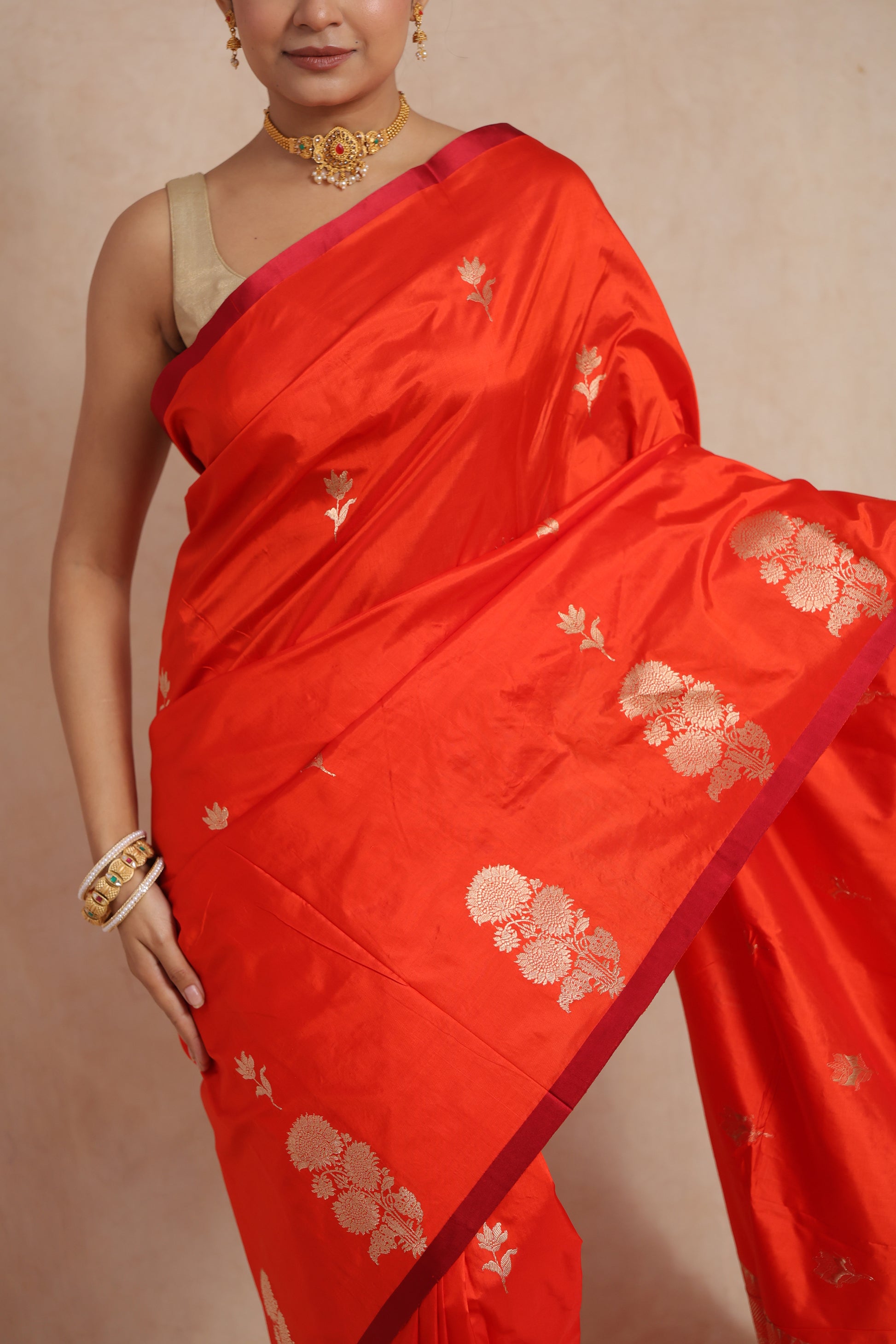 Close-up of the vermilion Banarasi silk saree highlighting floral motifs and elegant border