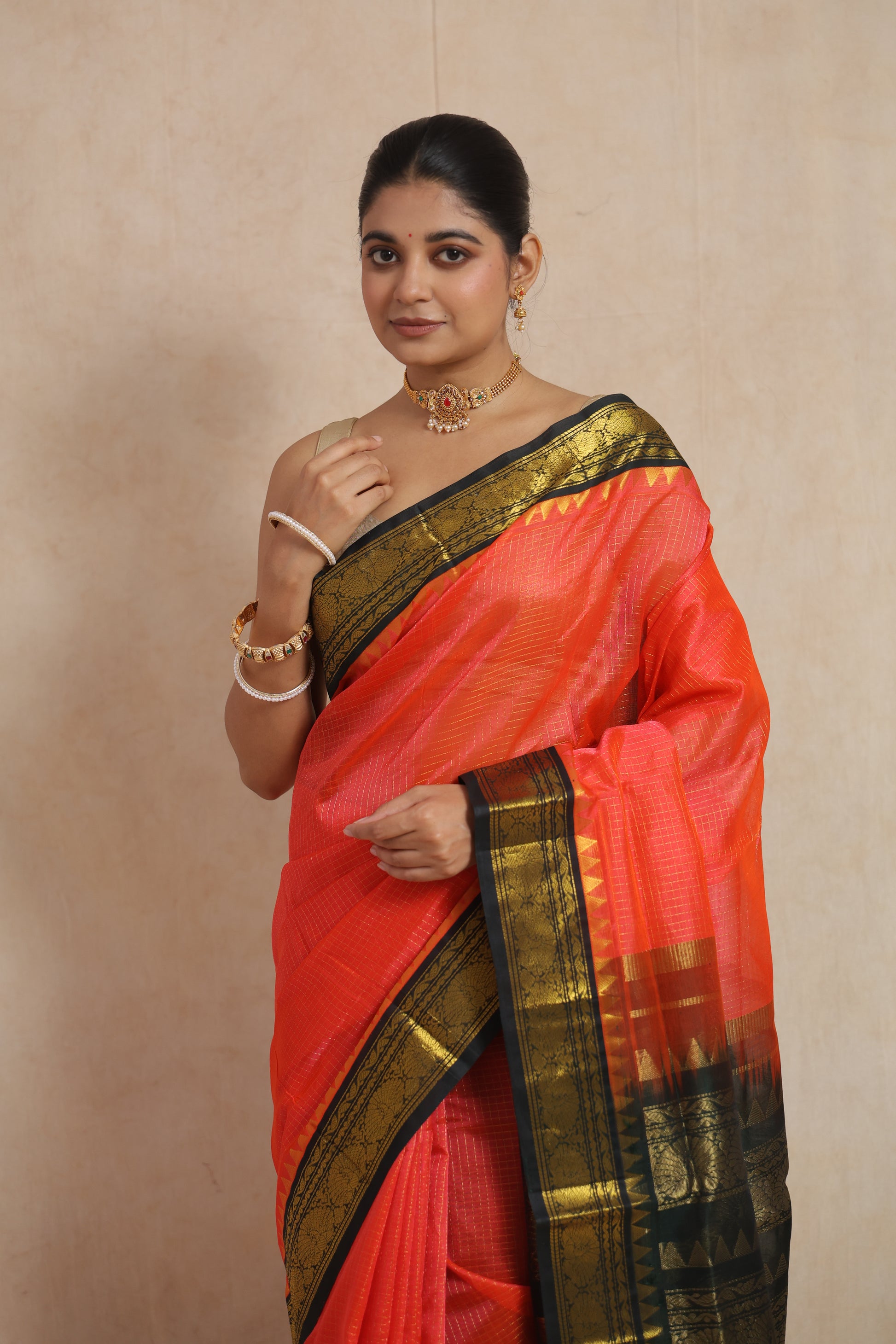 Portrait view of coral orange handloom SICO saree featuring traditional woven border