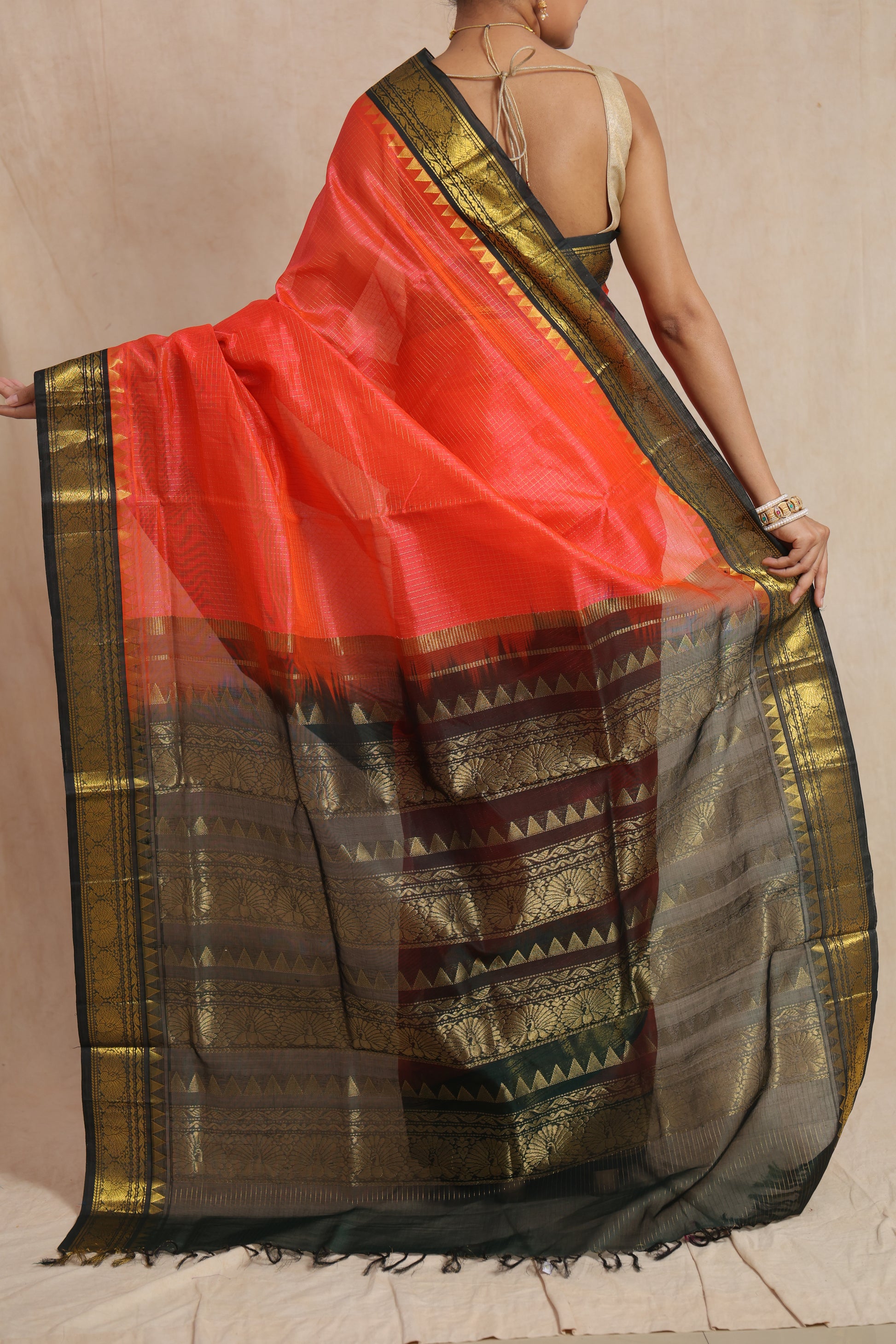 Detailed view of black contrast pallu with traditional woven motifs on coral orange saree