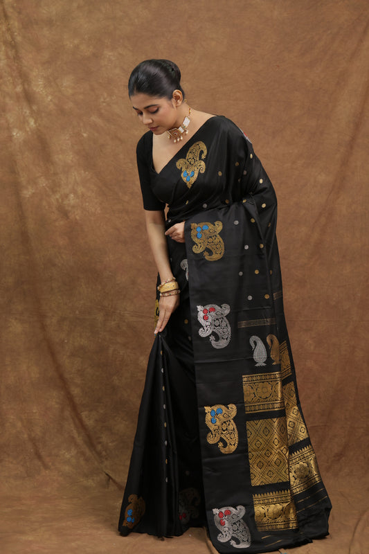 Midnight black Gadwal silk saree with multicolor floral motifs and a richly woven pallu, designed by Joyee Kolkata.