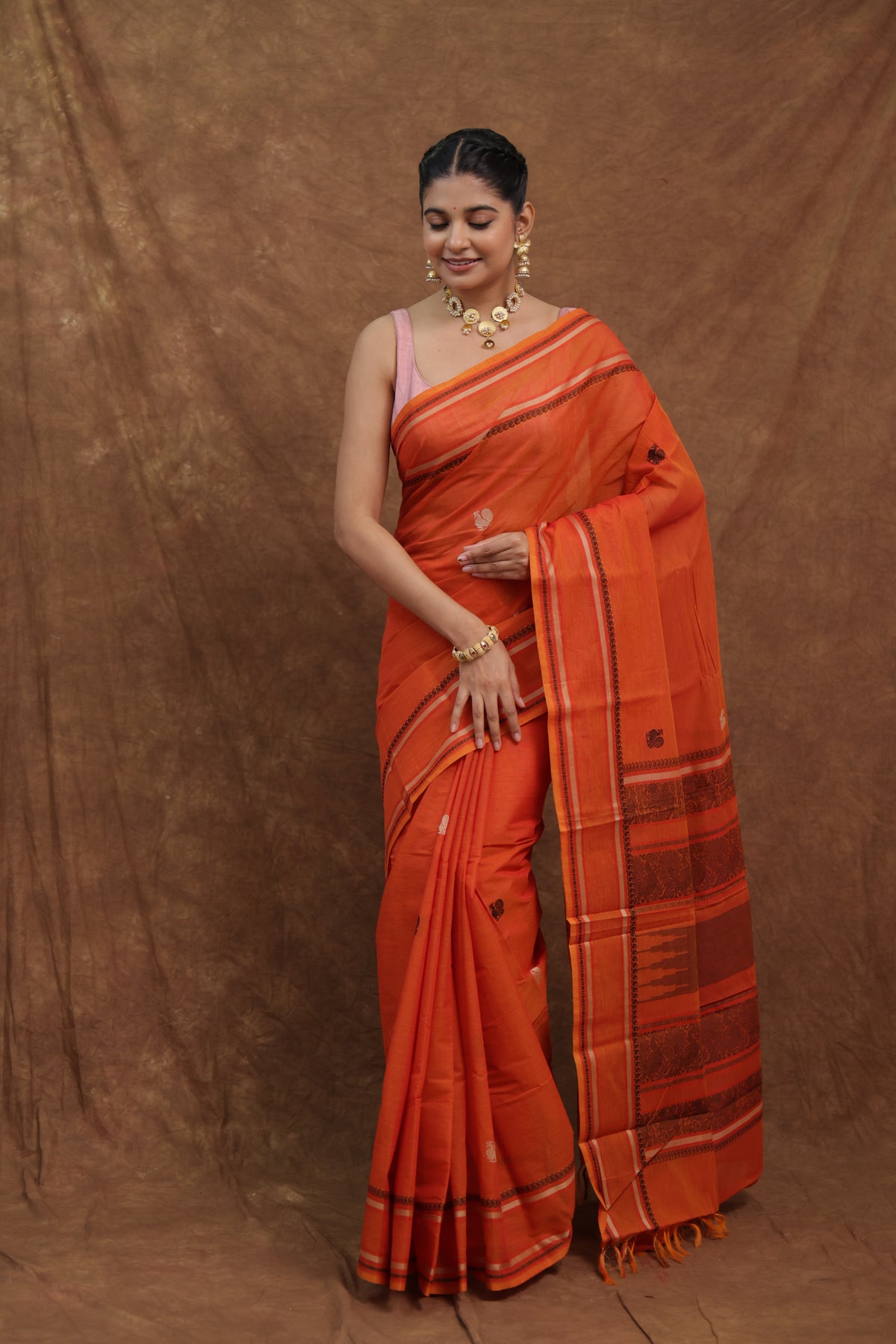 Pink Kanchipuram cotton saree with traditional woven border by Joyee Kolkata, showcasing intricate weaving and vibrant fabric.