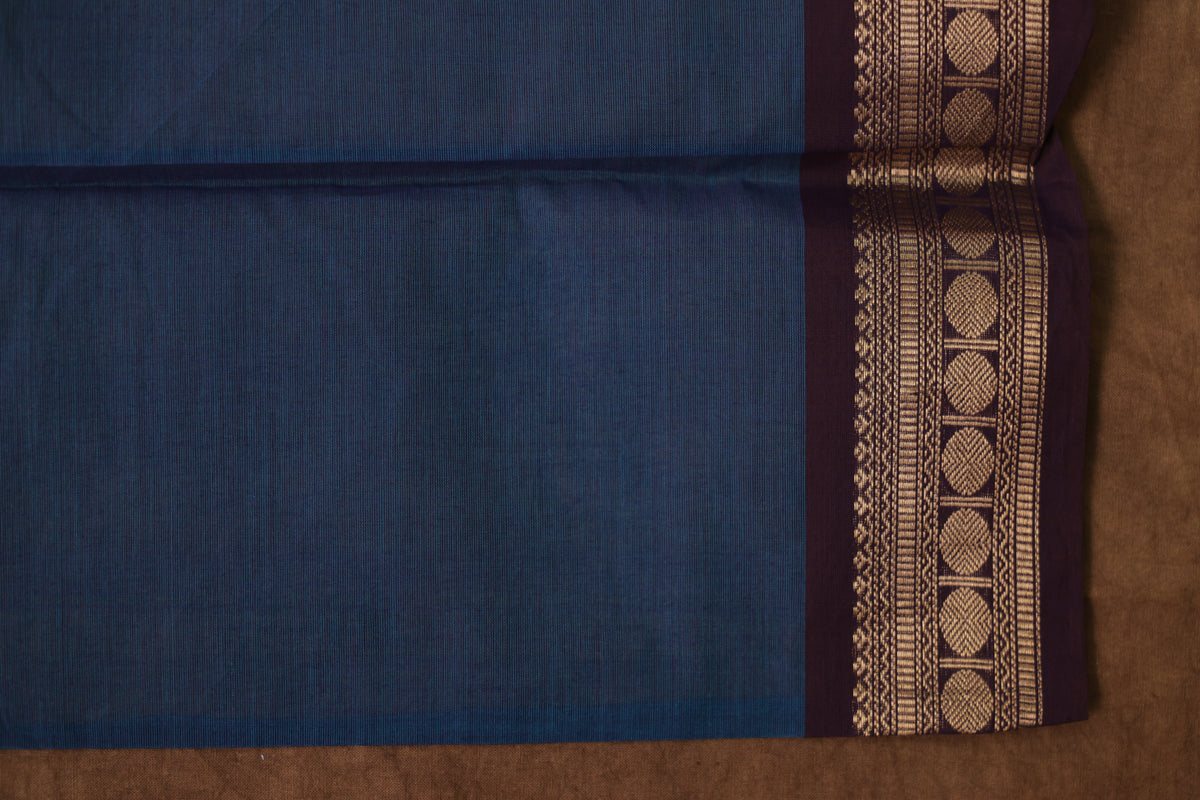 Blue Kanchipuram cotton saree with rust woven border, traditional denim blue sari by Joyee Kolkata displayed on a model.
