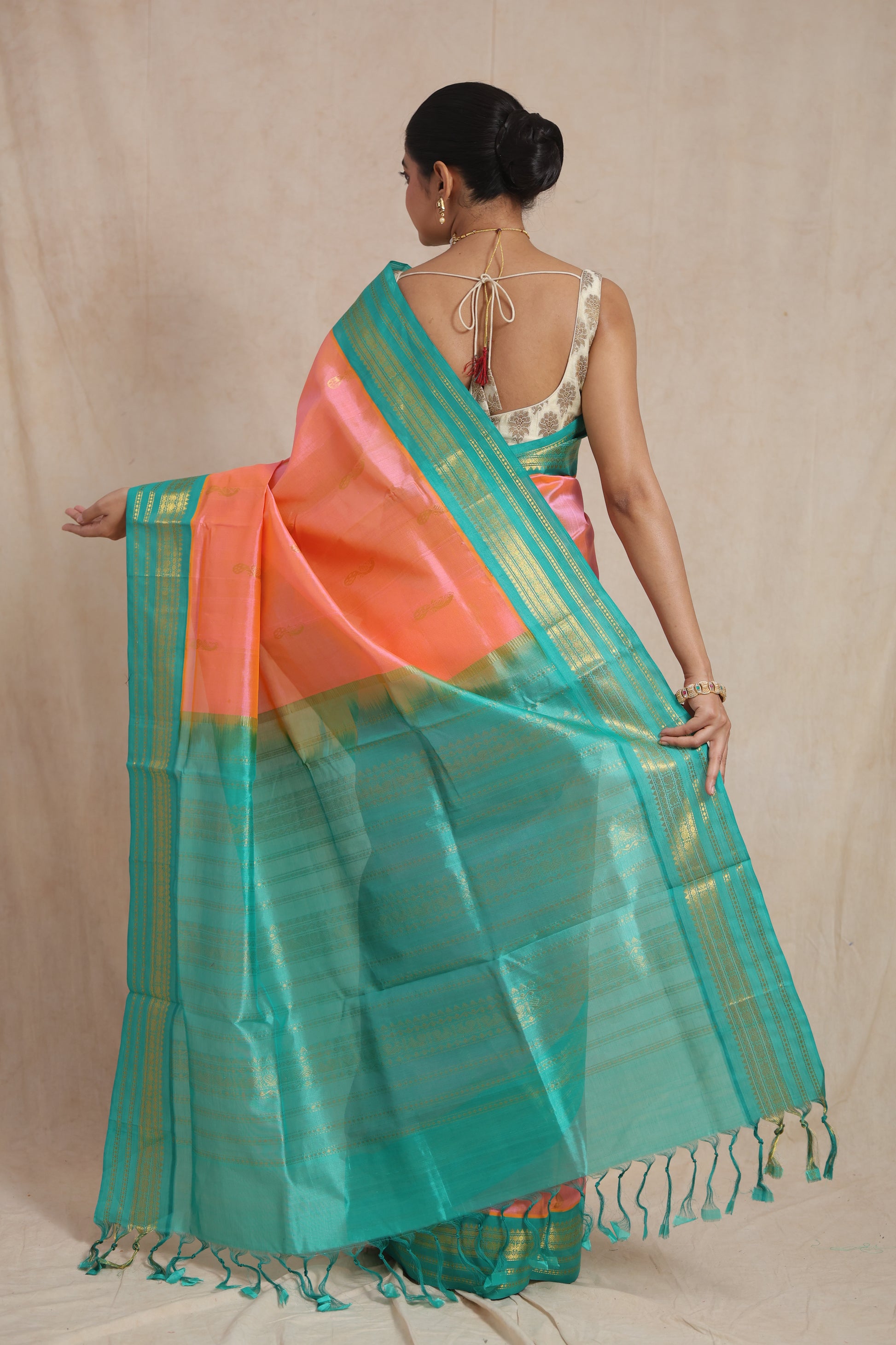 Back view of peach pink Kanchipuram Sico saree with aqua blue woven pallu and tassels