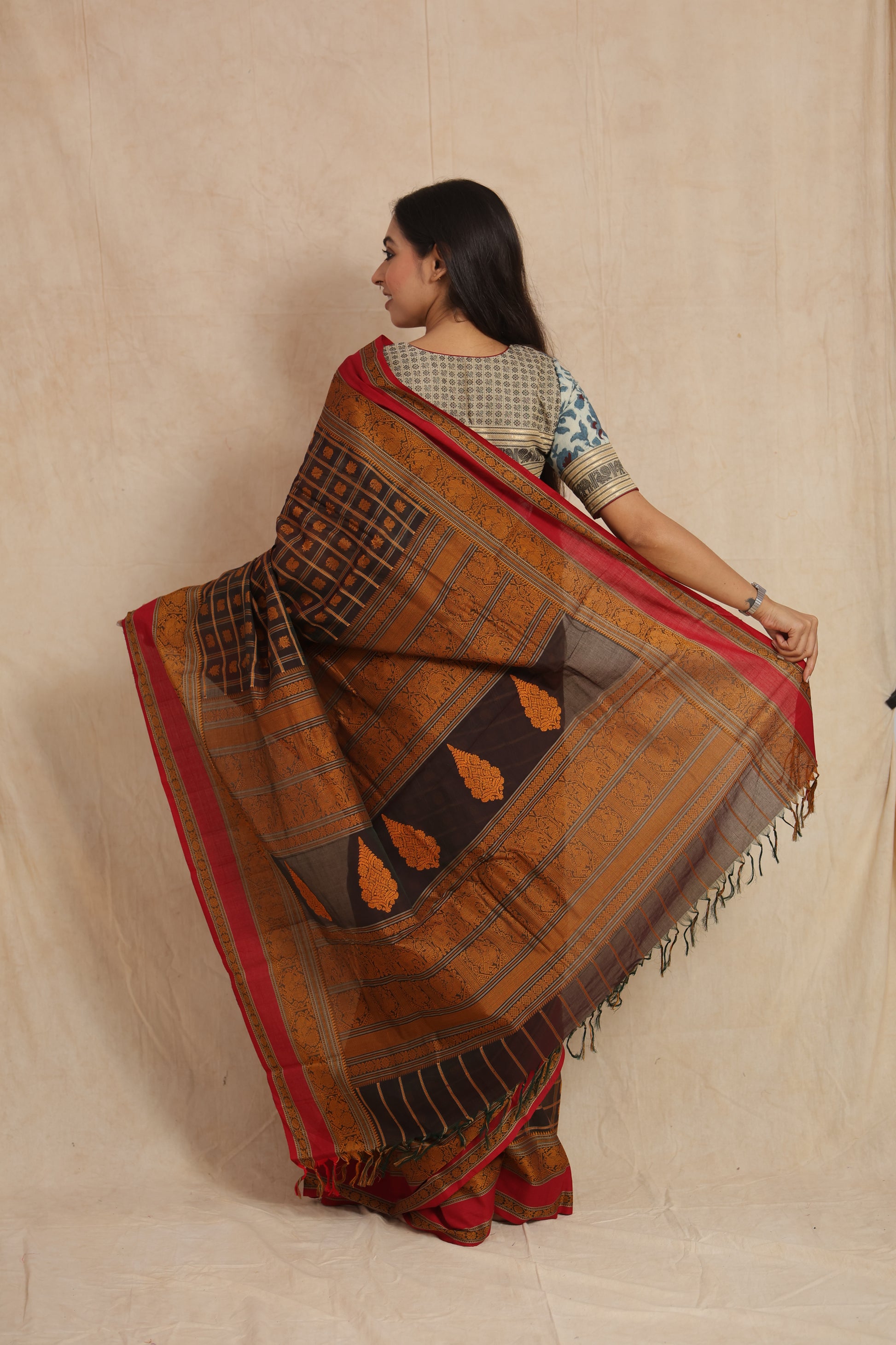 Back view of black Kanchipuram cotton saree with ornate woven pallu and red border