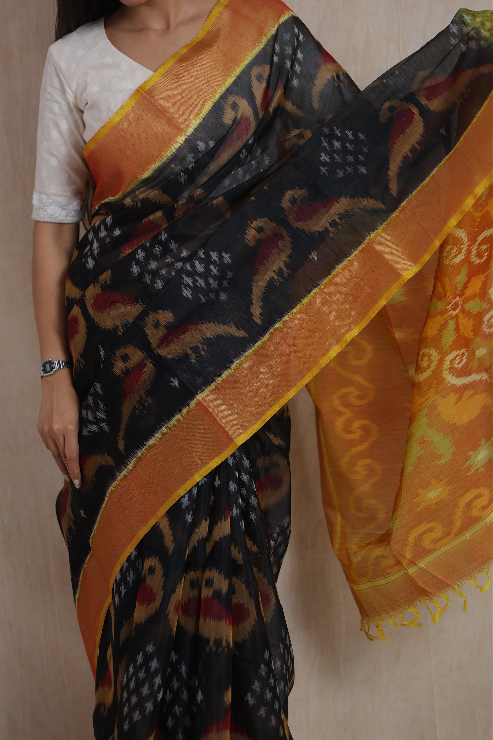 Close-up of black Panchampali silk cotton saree featuring traditional Ikat motifs and orange border
