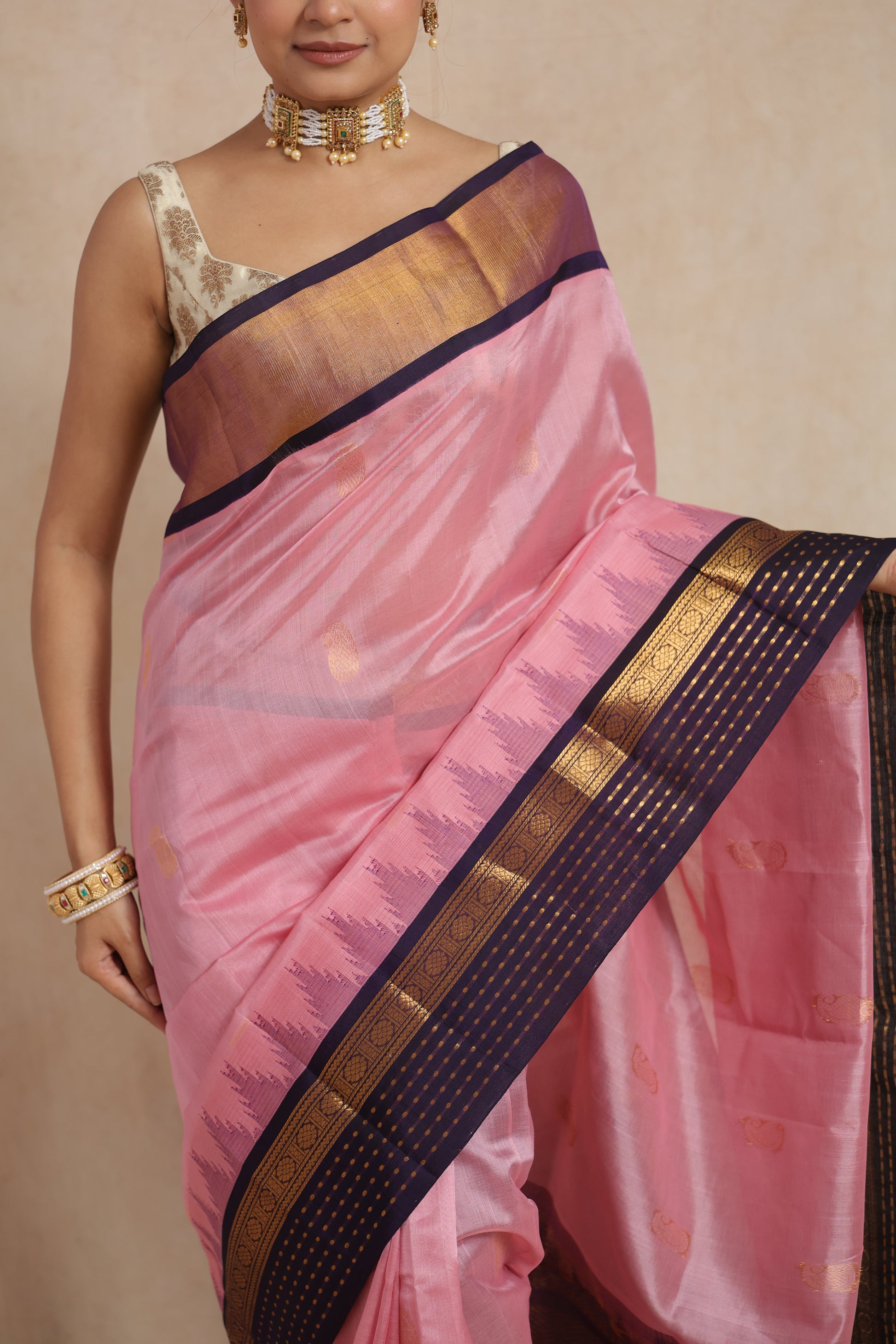 Close-up of blush pink Kanchipuram Sico saree with purple zari border and buttas