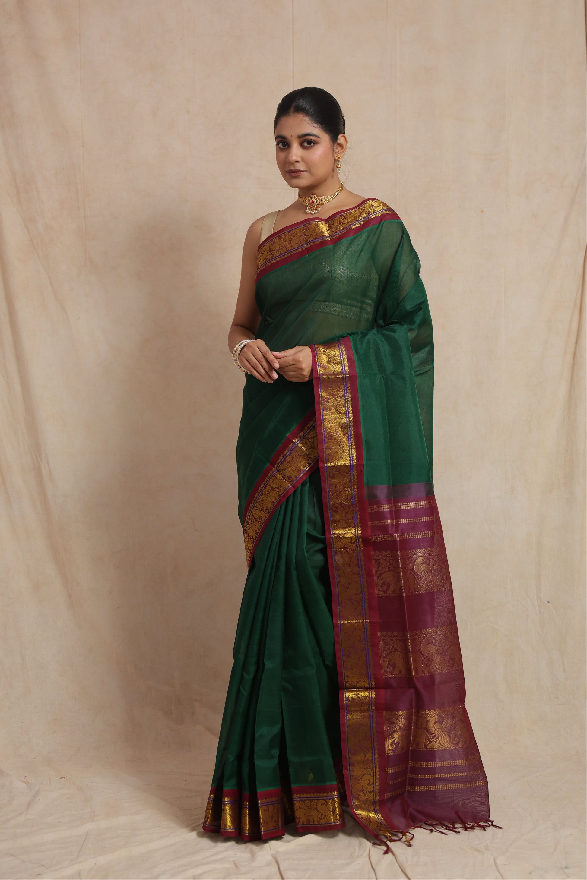 Front view of emerald green Kanchipuram SICO saree with wine purple traditional woven border and pallu