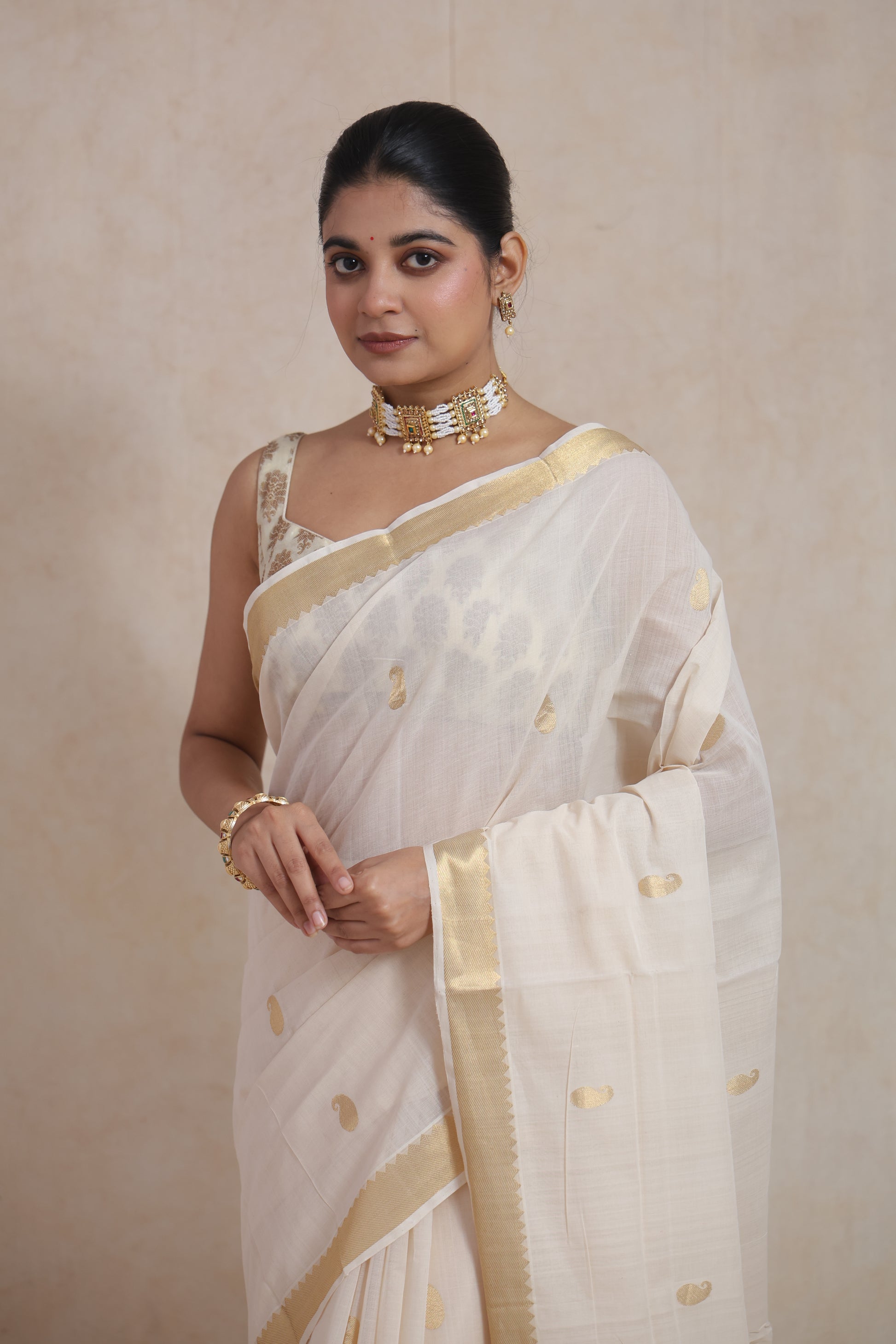Close-up of off white Kanchipuram cotton saree with golden buttas and woven border