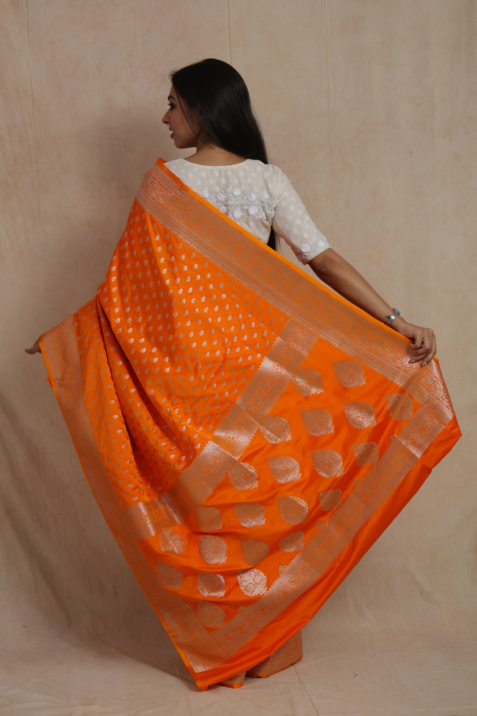 Back view of orange Banarasi silk saree showcasing elaborate woven zari pallu.
