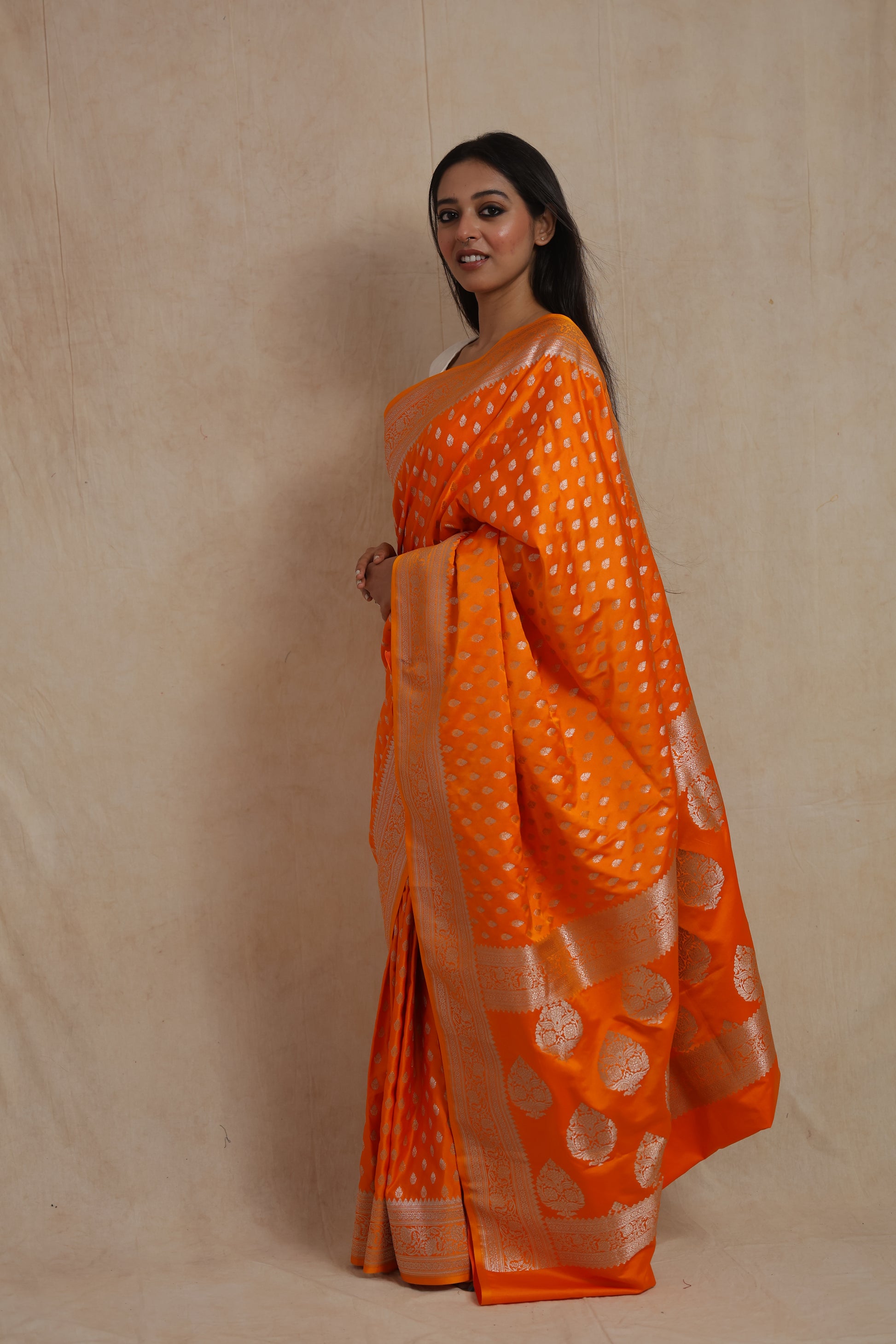 Side profile of orange Banarasi saree featuring silver zari motifs and rich pallu.