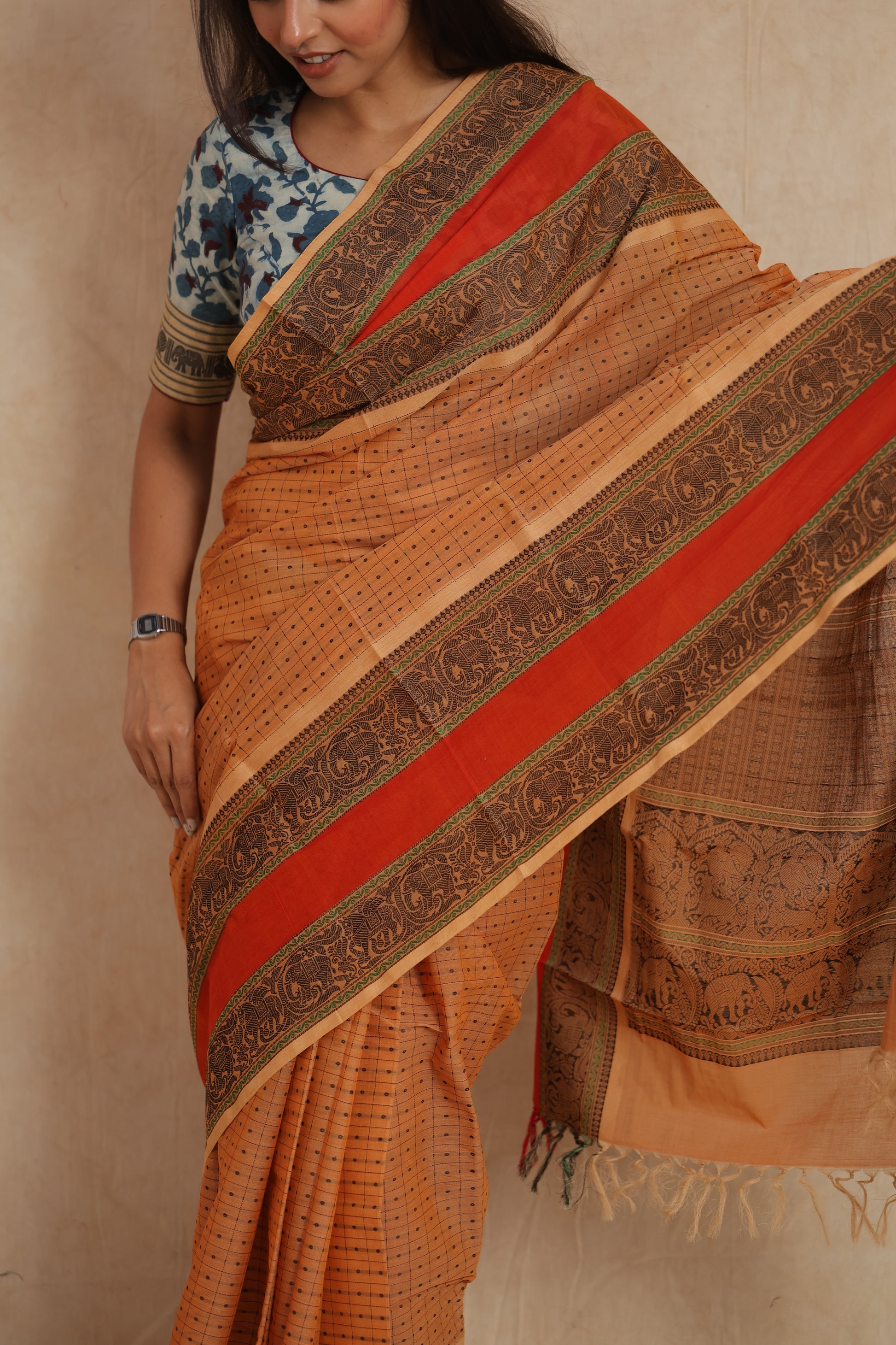 Close-up drape of beige Kanchipuram cotton saree with red and black woven border