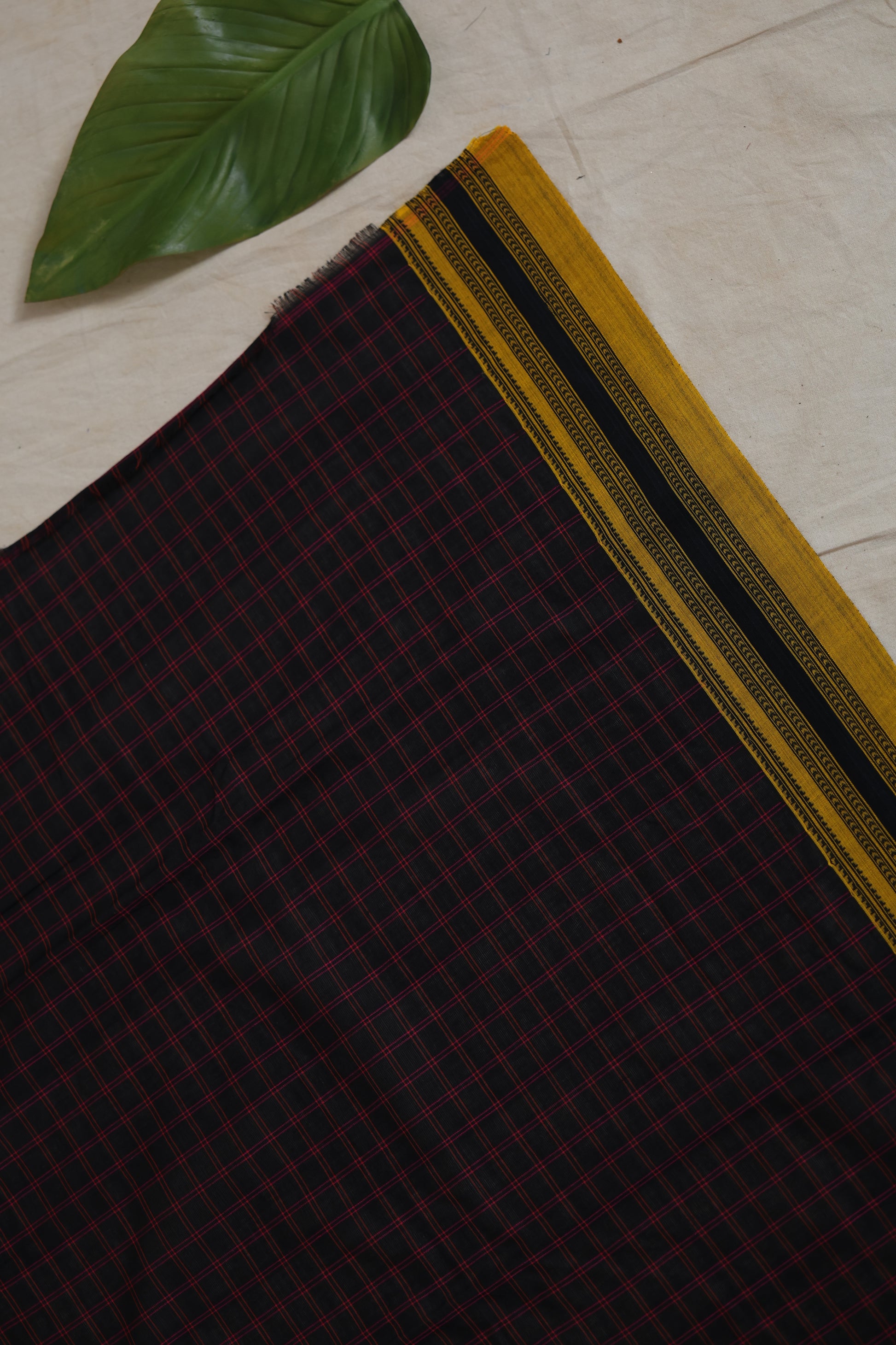Elegant drape of black checked Ilak cotton saree with woven mustard border