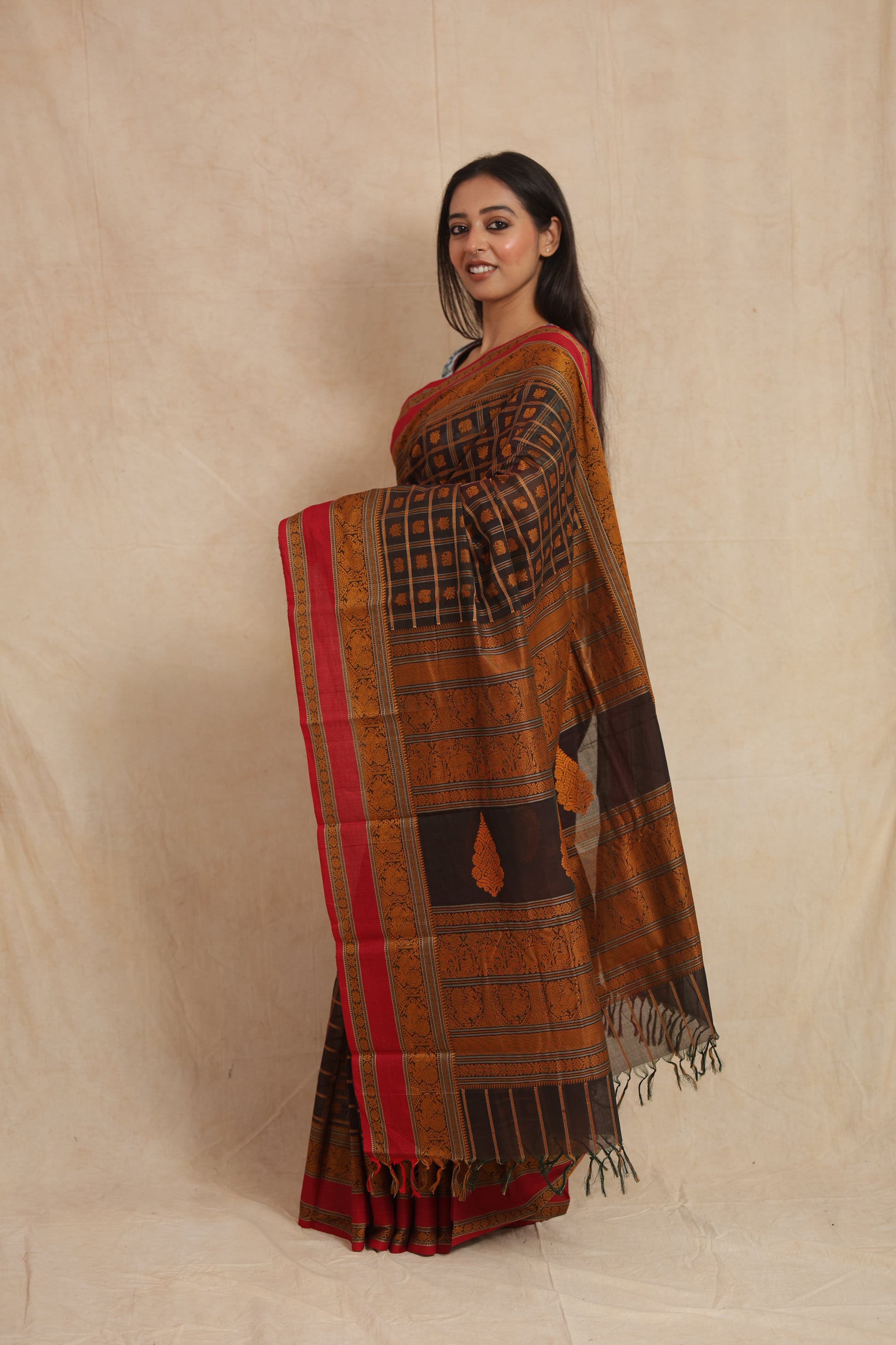 Side profile of black Kanchipuram cotton saree with copper woven detailing and tassels