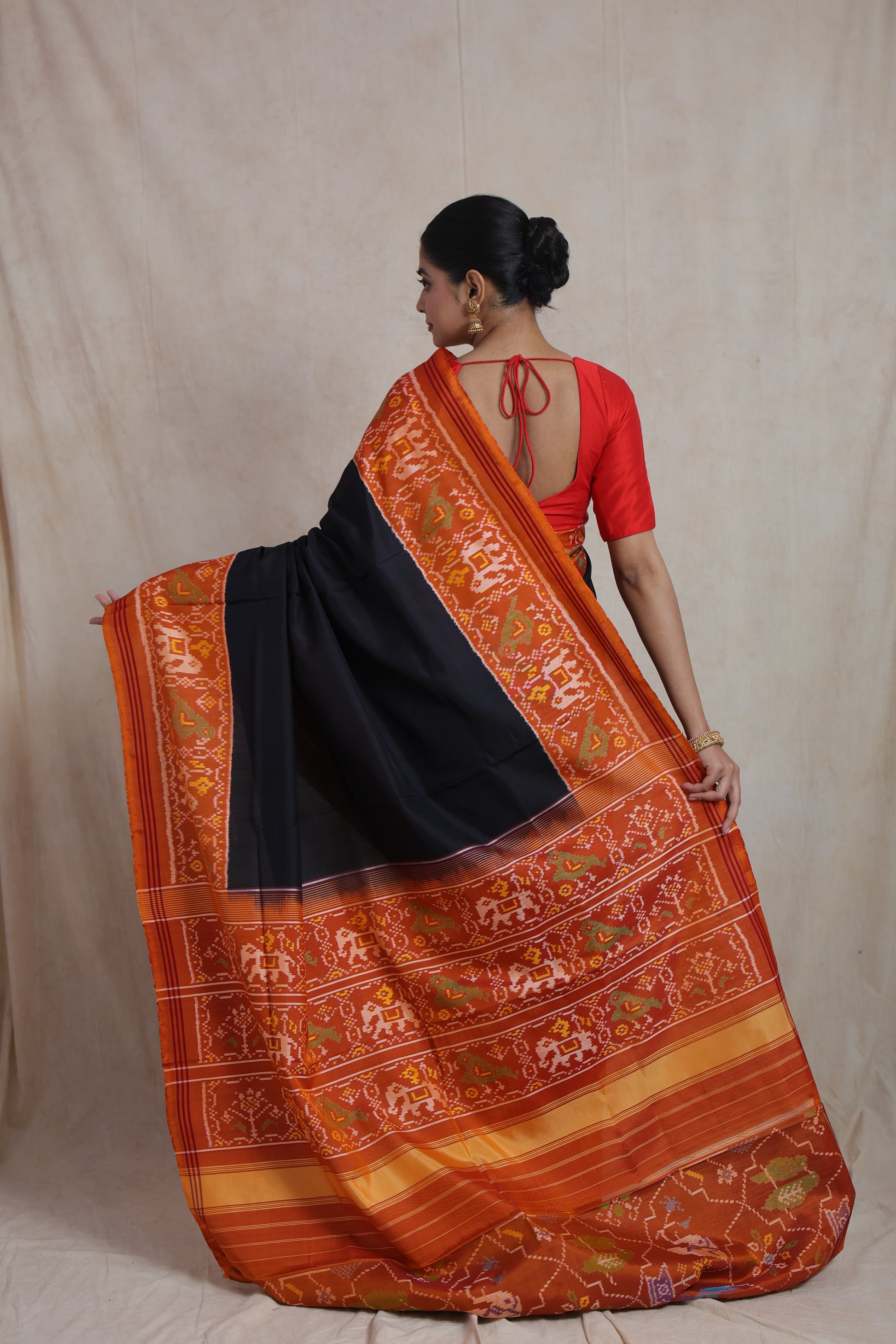 Back view of black Patola silk saree with rust orange woven border
