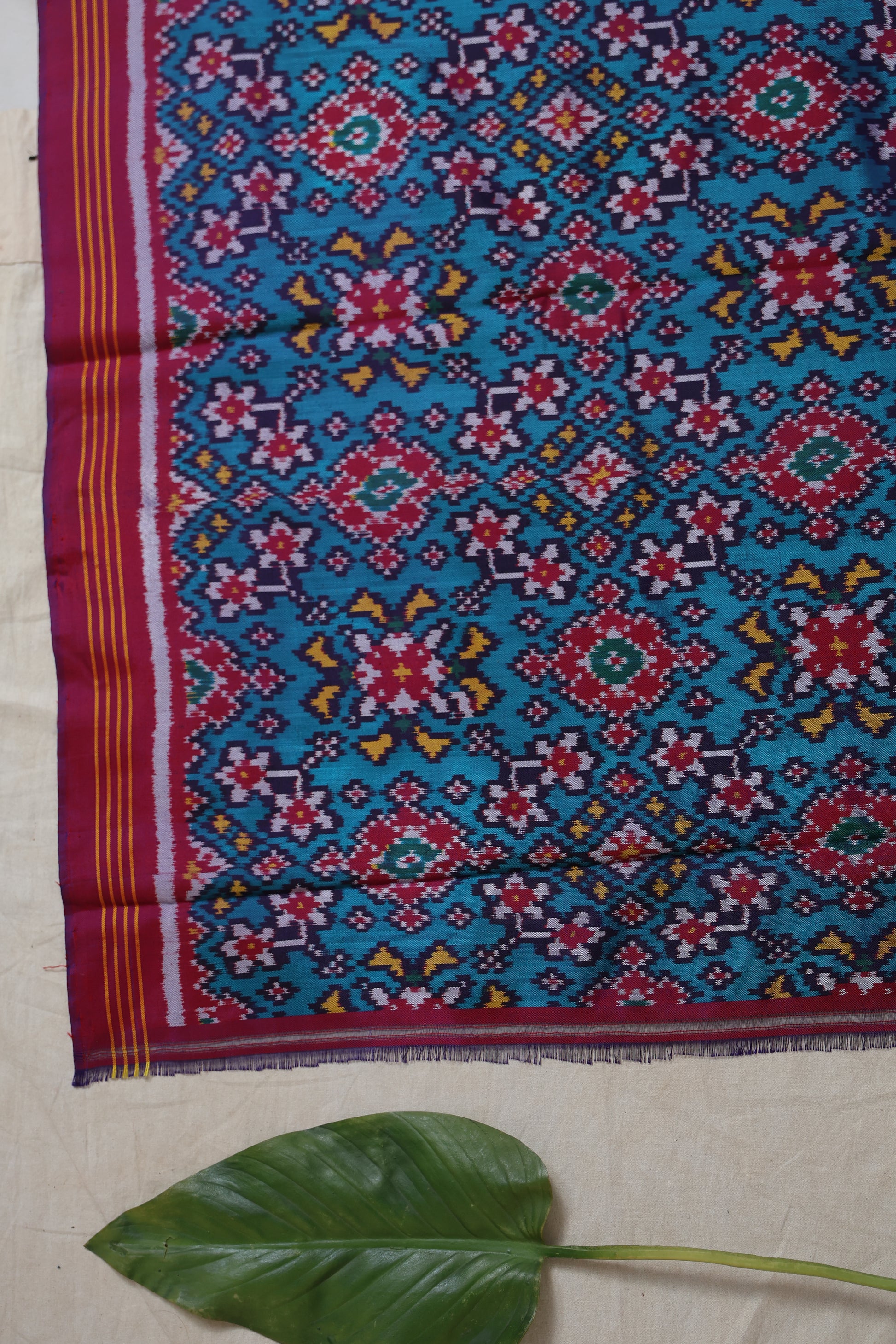 Close-up of blush pink Patola handloom silk saree featuring intricate multicolor ikat woven motifs