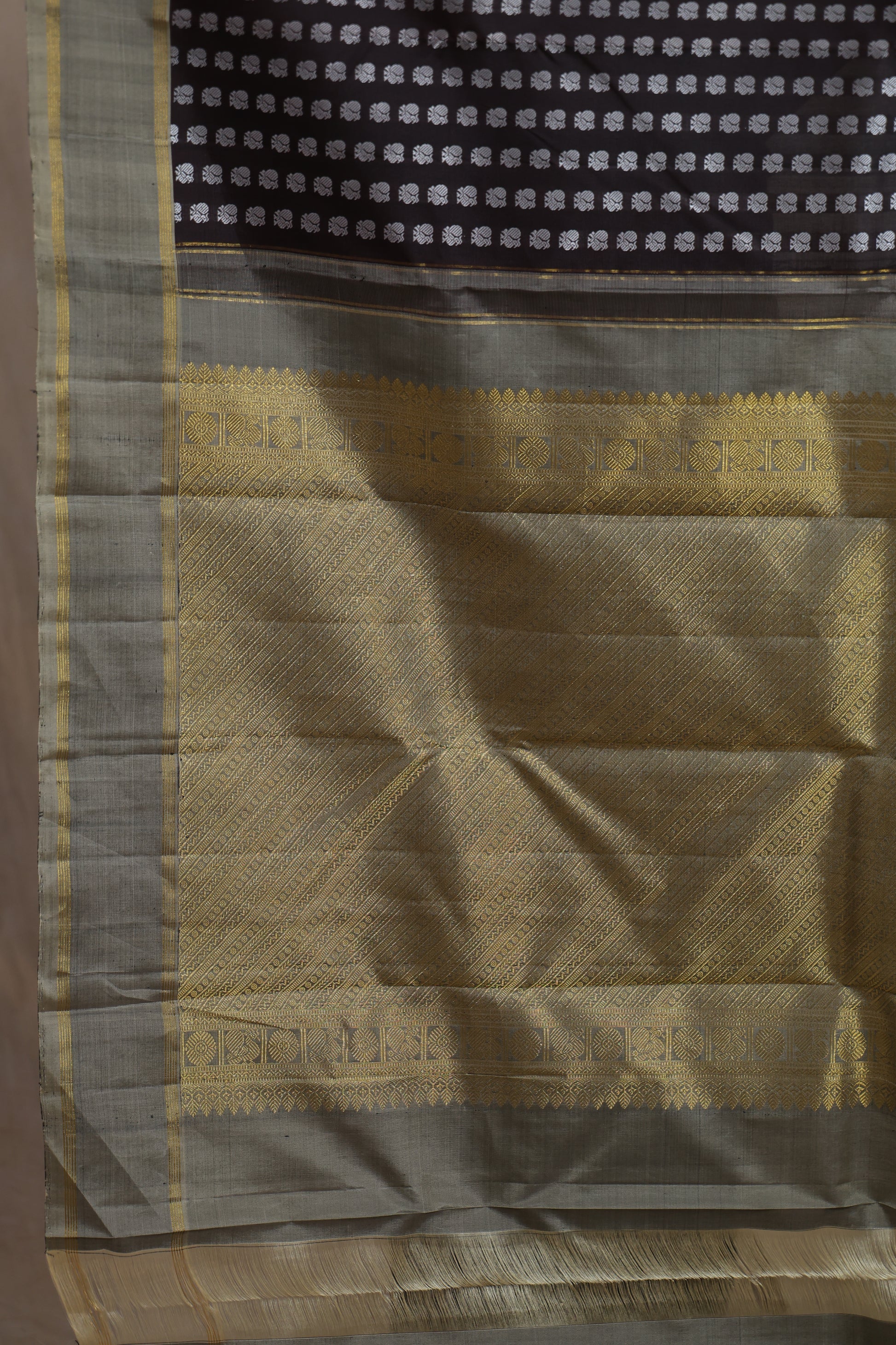Close-up of gold zari woven pallu on deep brown Kanjivaram silk saree
