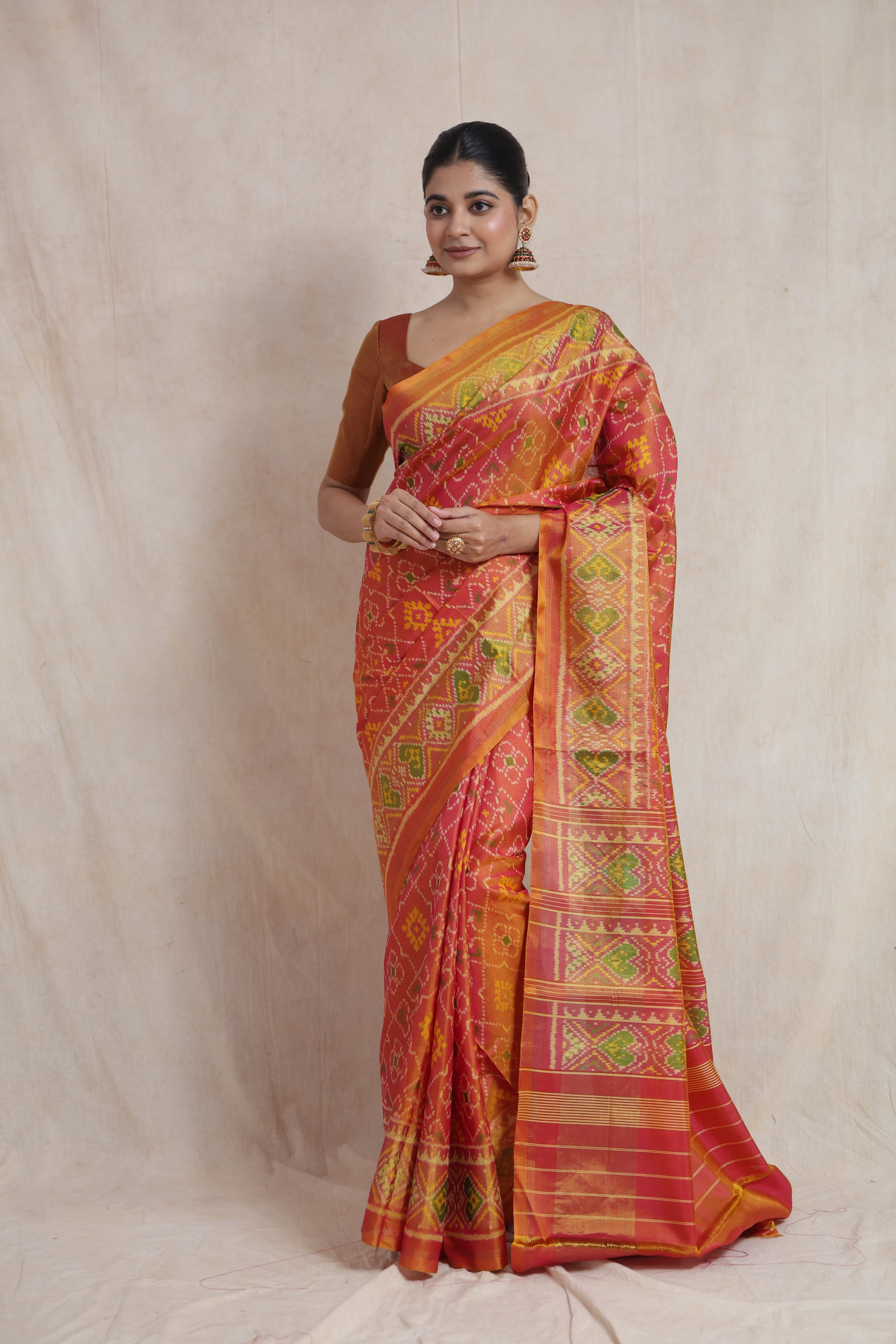 Front drape view of coral and orange Patola silk saree with heritage-inspired ikat weaving