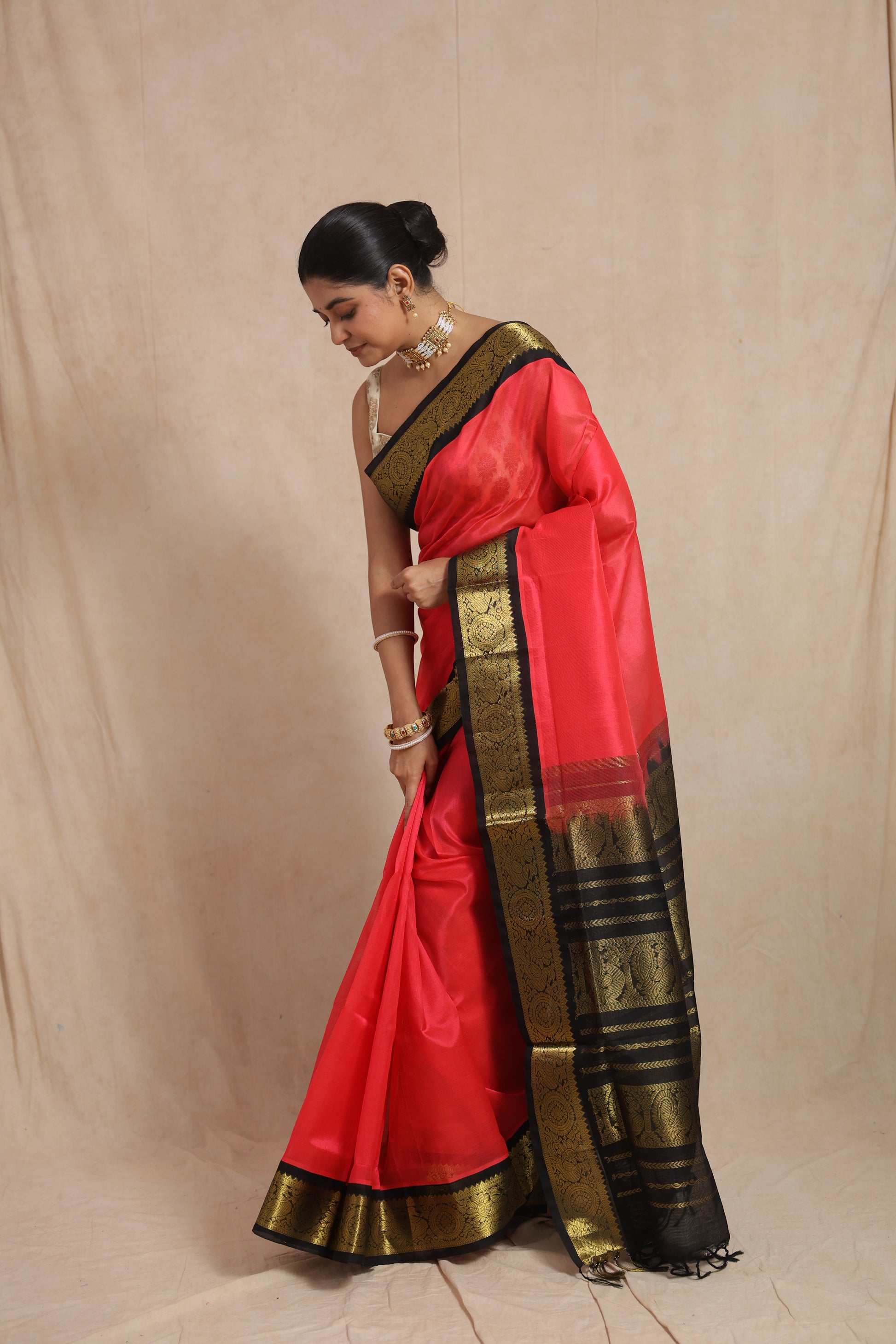 Elegant drape style of coral pink Kanchipuram Sico saree with woven zari border