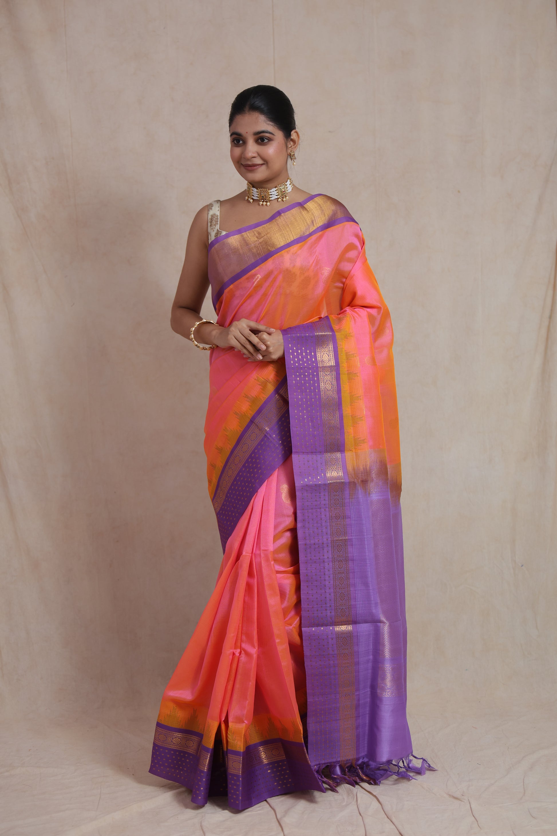 Model wearing coral pink Kanchipuram silk cotton saree with lavender zari border front view