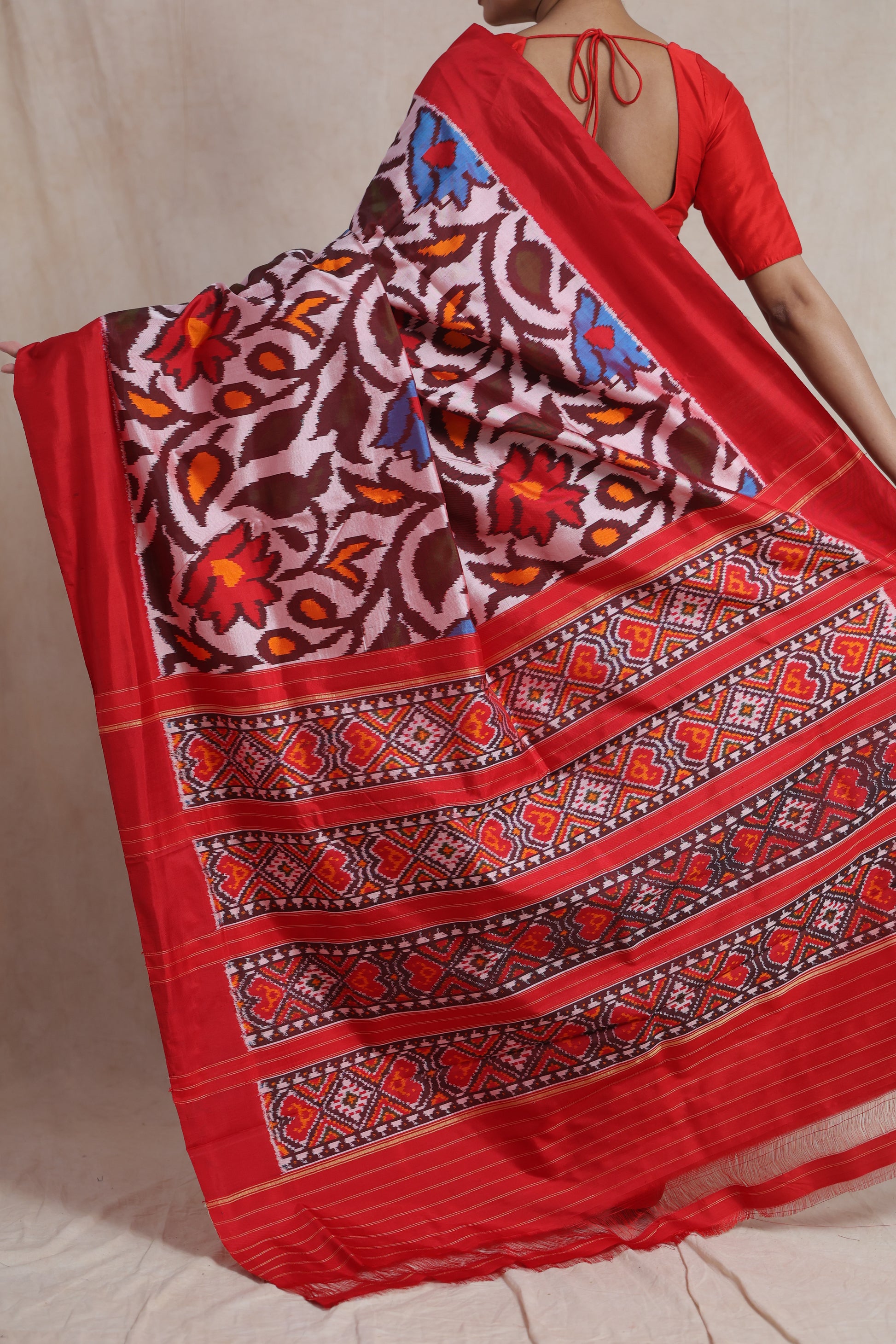 Back view of crimson red Pochampally handloom silk saree showcasing floral ikat motifs and geometric woven pallu