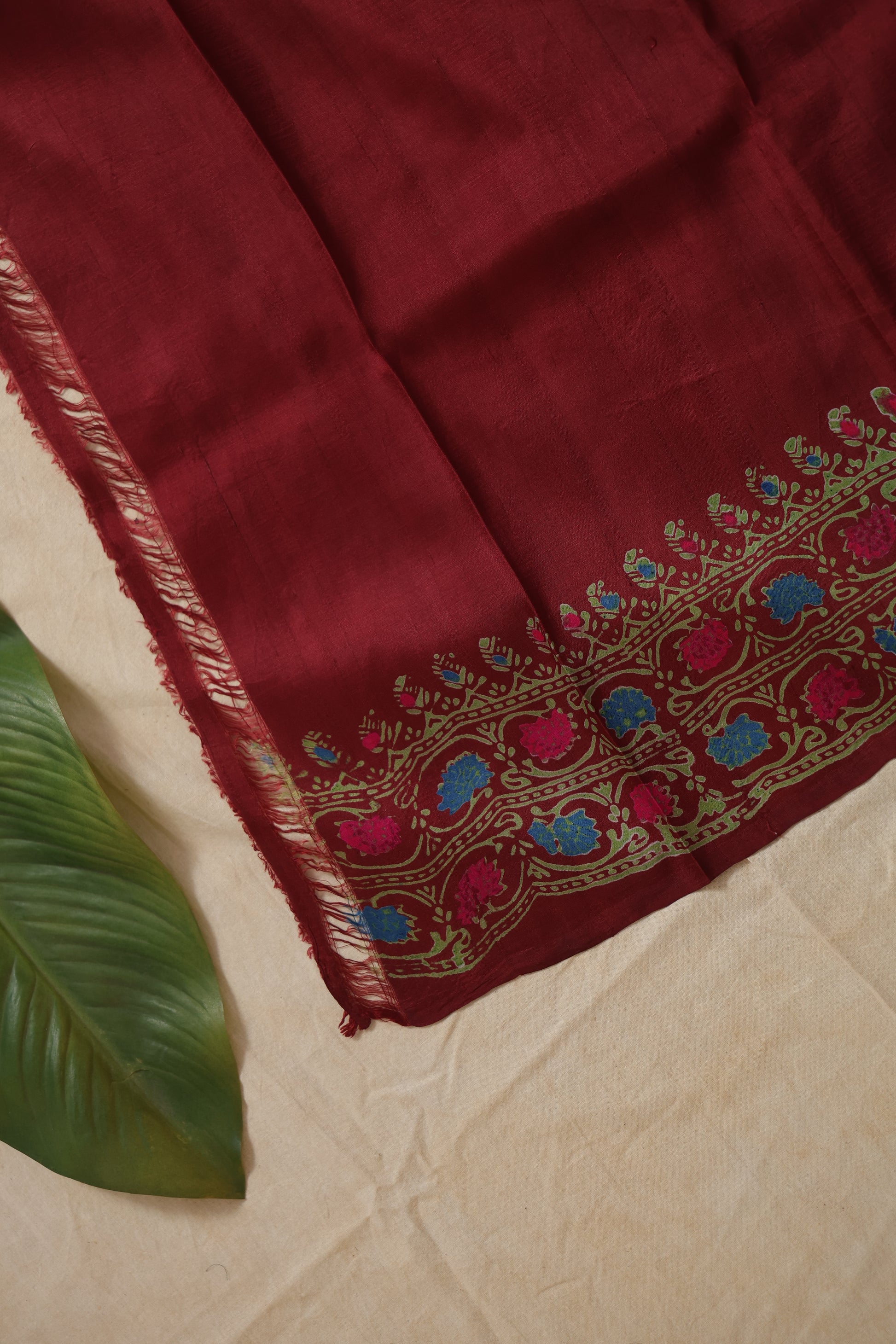 Close-up detail of deep maroon Batik silk saree with multicolor floral border