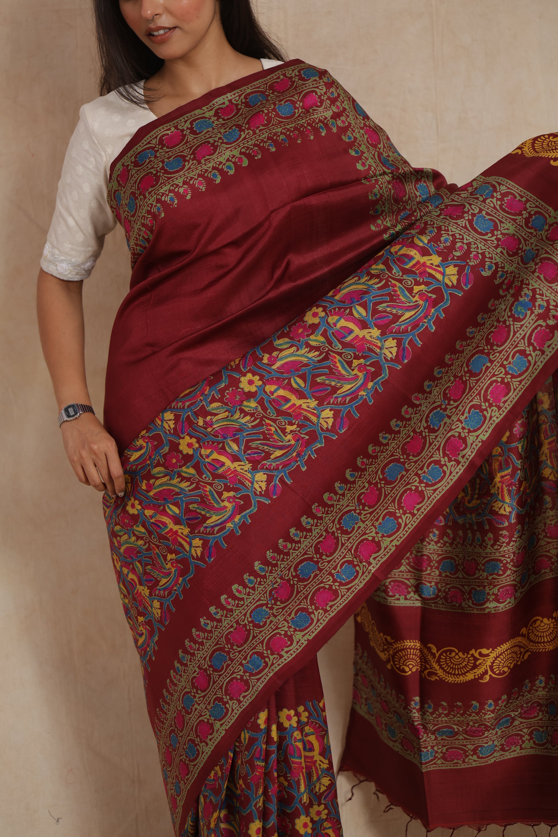 Elegant close-up of deep maroon Batik silk saree with intricate multicolor border design