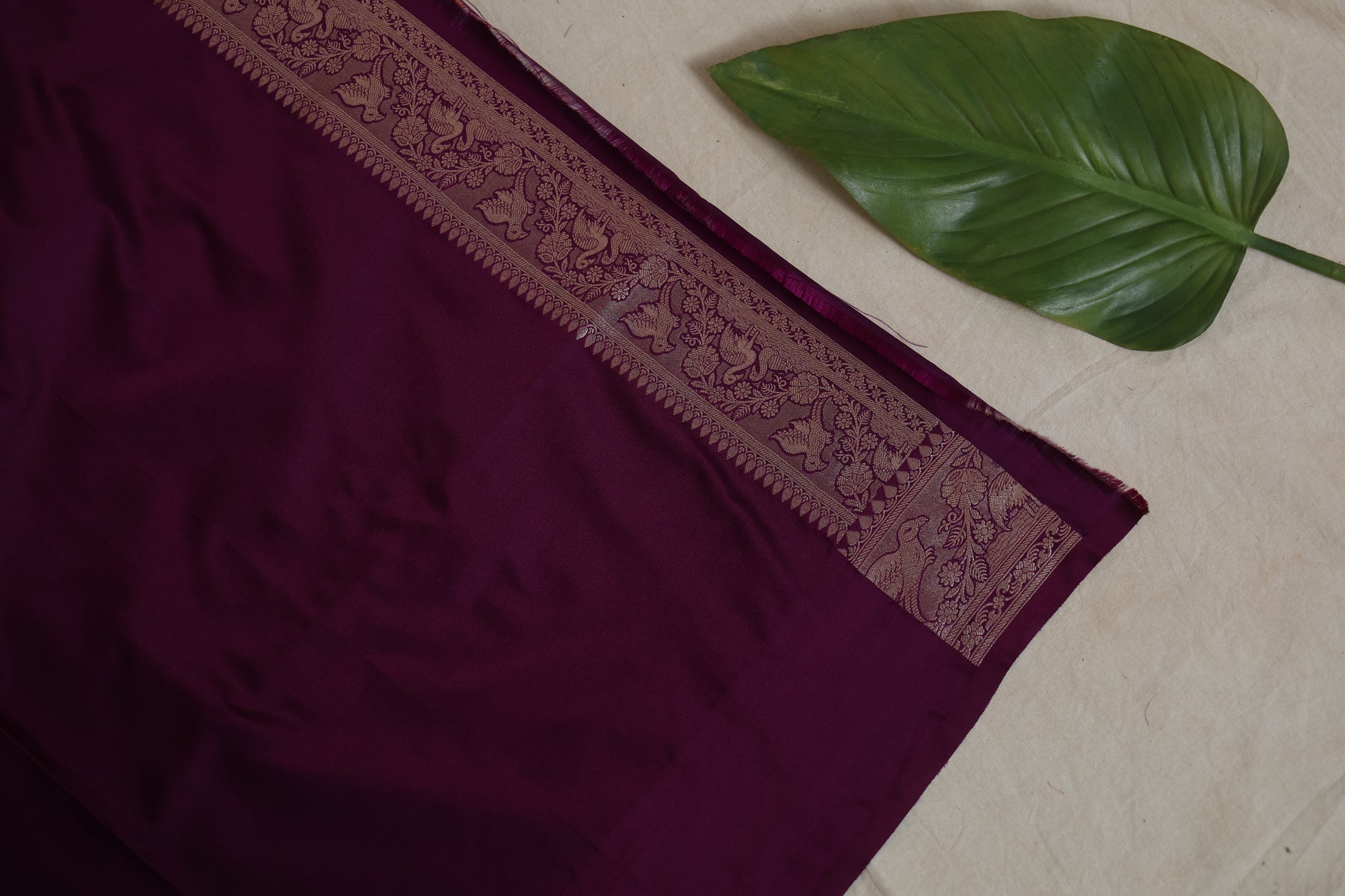 Close-up of intricate floral zari border on deep wine Banarasi silk saree.