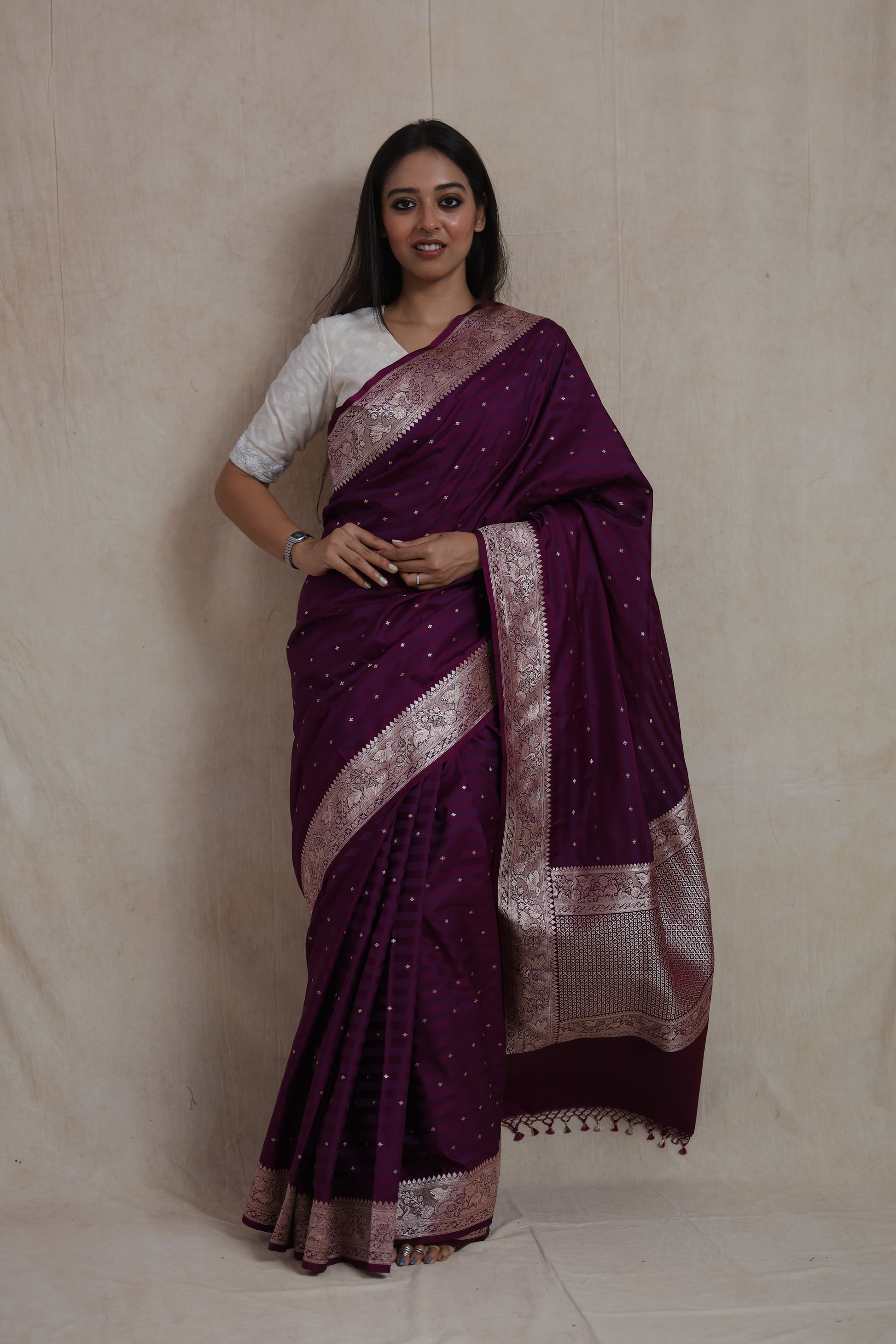Model wearing deep wine Banarasi silk saree with silver zari buttas and woven border.