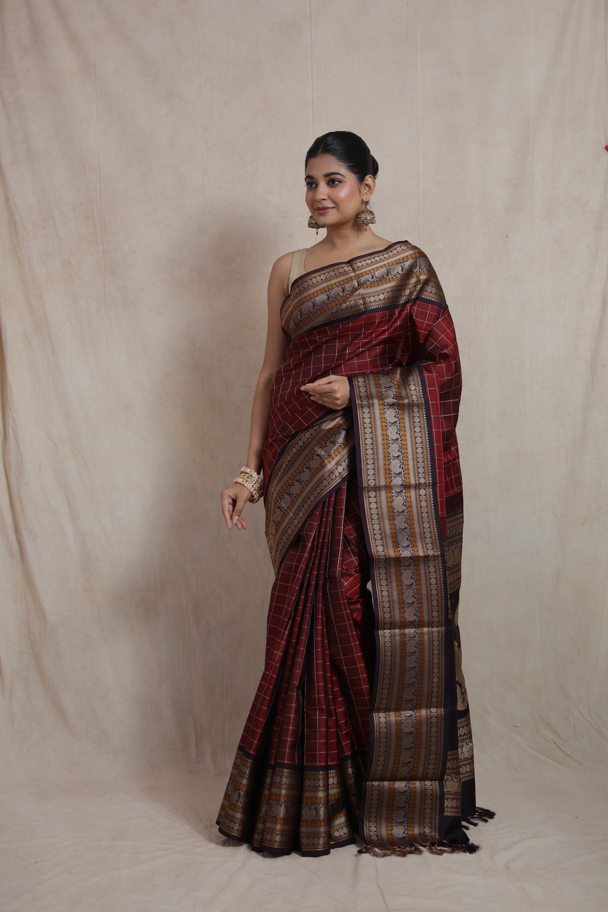 Side pose of deep wine Kanjeevaram silk saree featuring intricate zari detailing