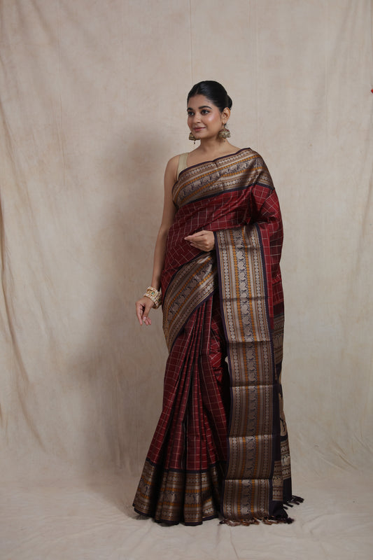 Side pose of deep wine Kanjeevaram silk saree featuring intricate zari detailing