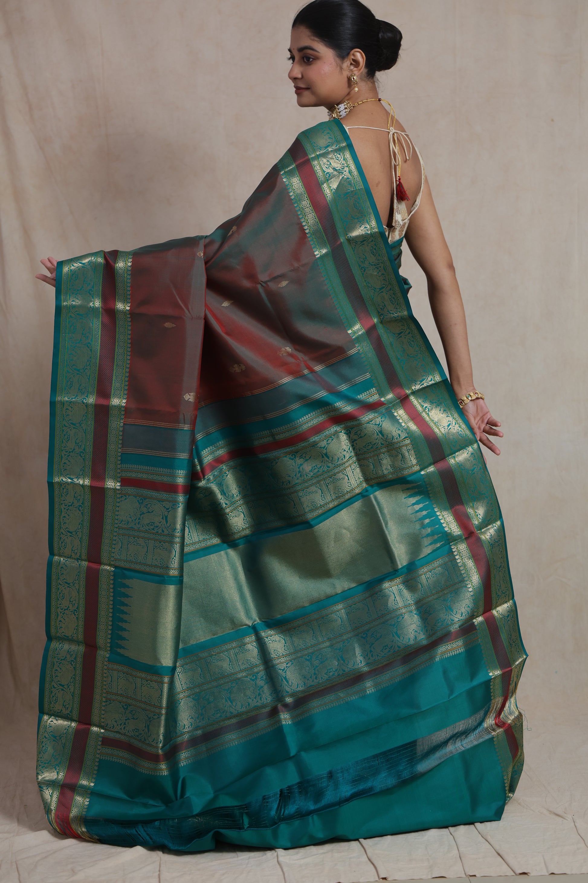 Close-up of dual-tone Kanchiwaram silk saree featuring teal zari border and buttas
