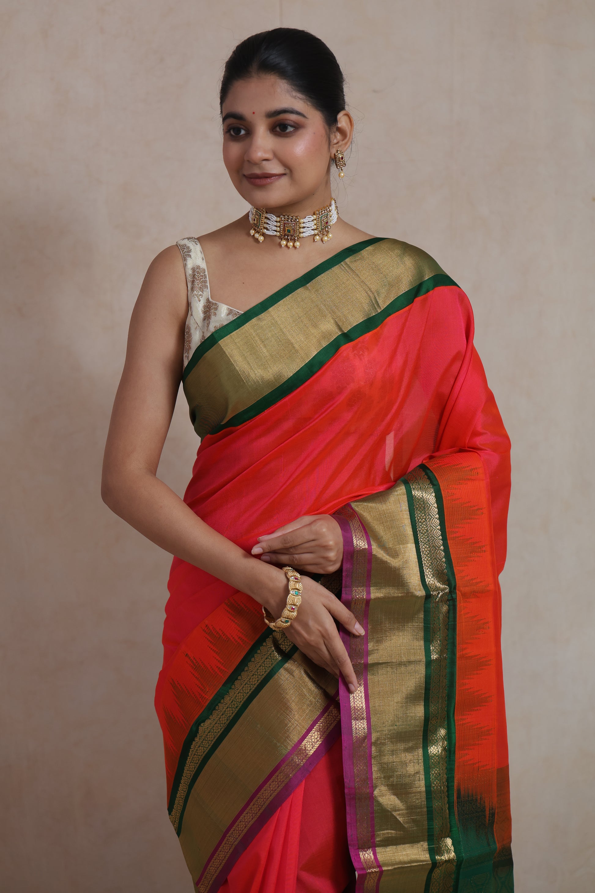 Elegant model shot of coral red Kanchipuram silk cotton saree with green border