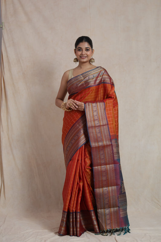 Model wearing rust orange Kanjivaram silk saree with royal blue zari pallu