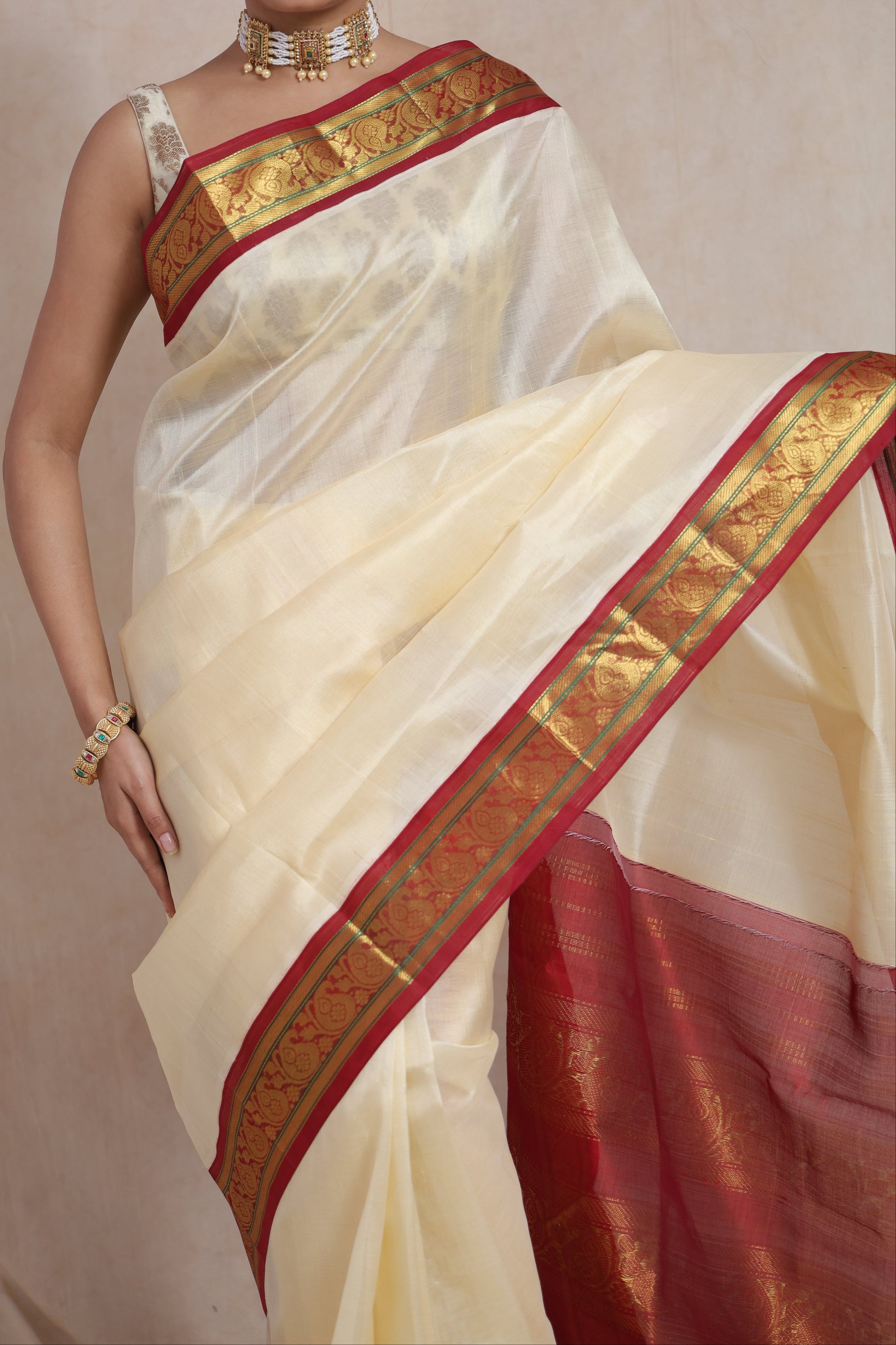 Close-up of elegant off-white Kanchipuram Sico saree with traditional red zari border
