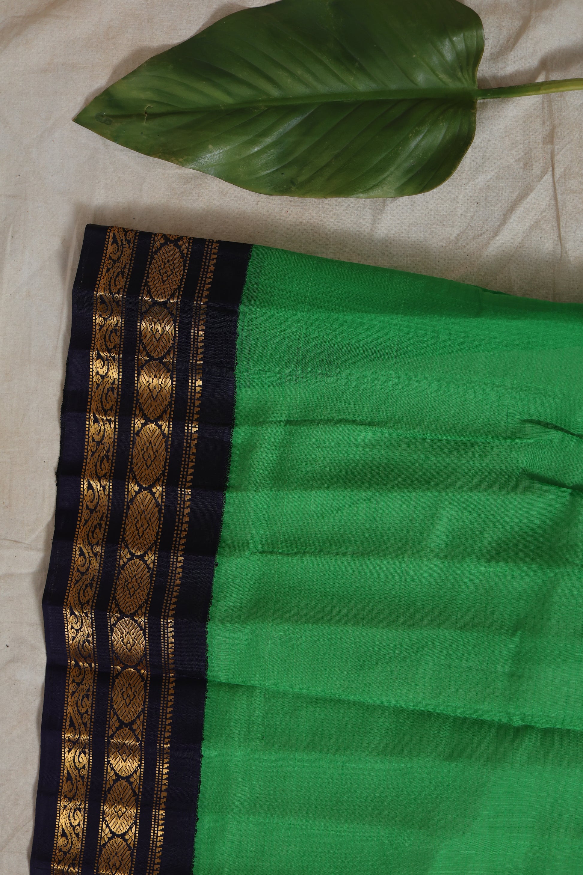 Emerald green Gadwal Sico saree with navy blue zari woven border flatlay view